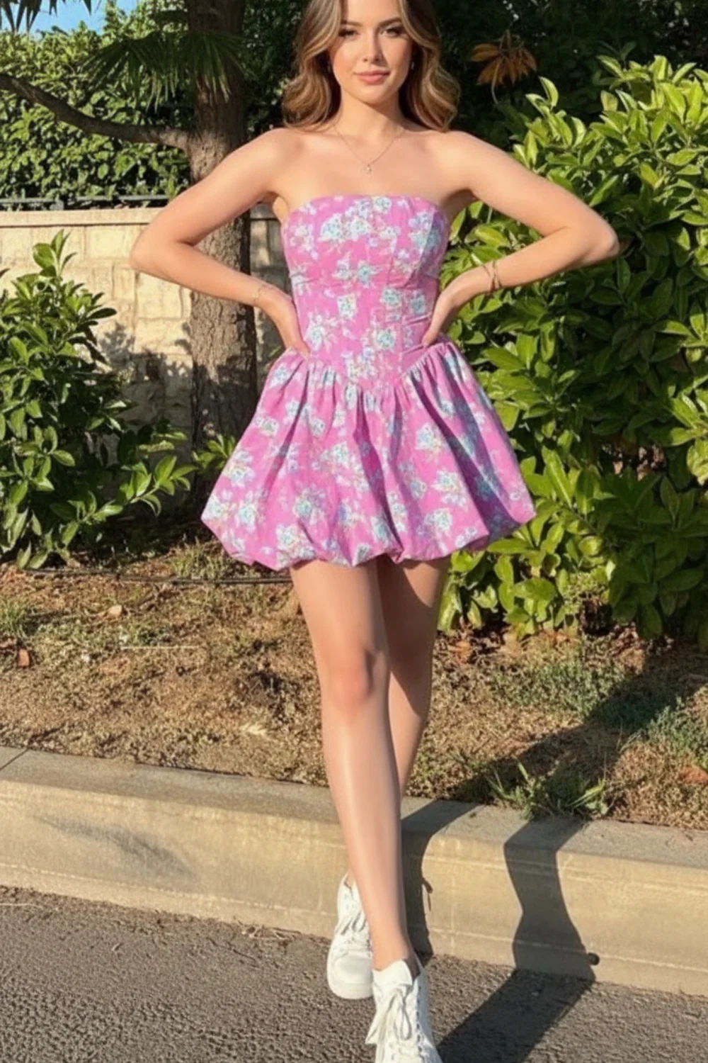 Woman wearing pink floral strapless corset mini dress with blue flowers and bubble skirt