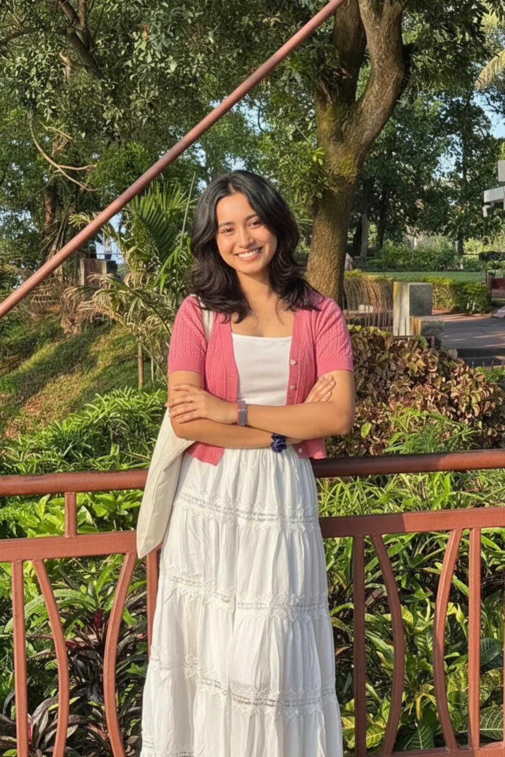 Woman wearing white cami top with pink ribbed cropped cardigan and white eyelet maxi skirt outdoors