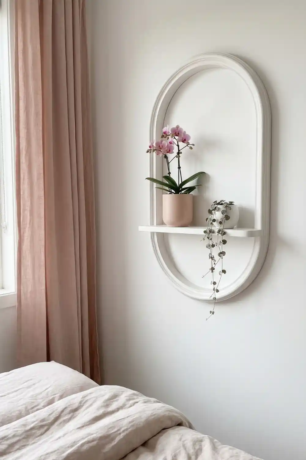 White arched wall mounted shelf with pink orchid and trailing string of hearts in blush ceramic pots