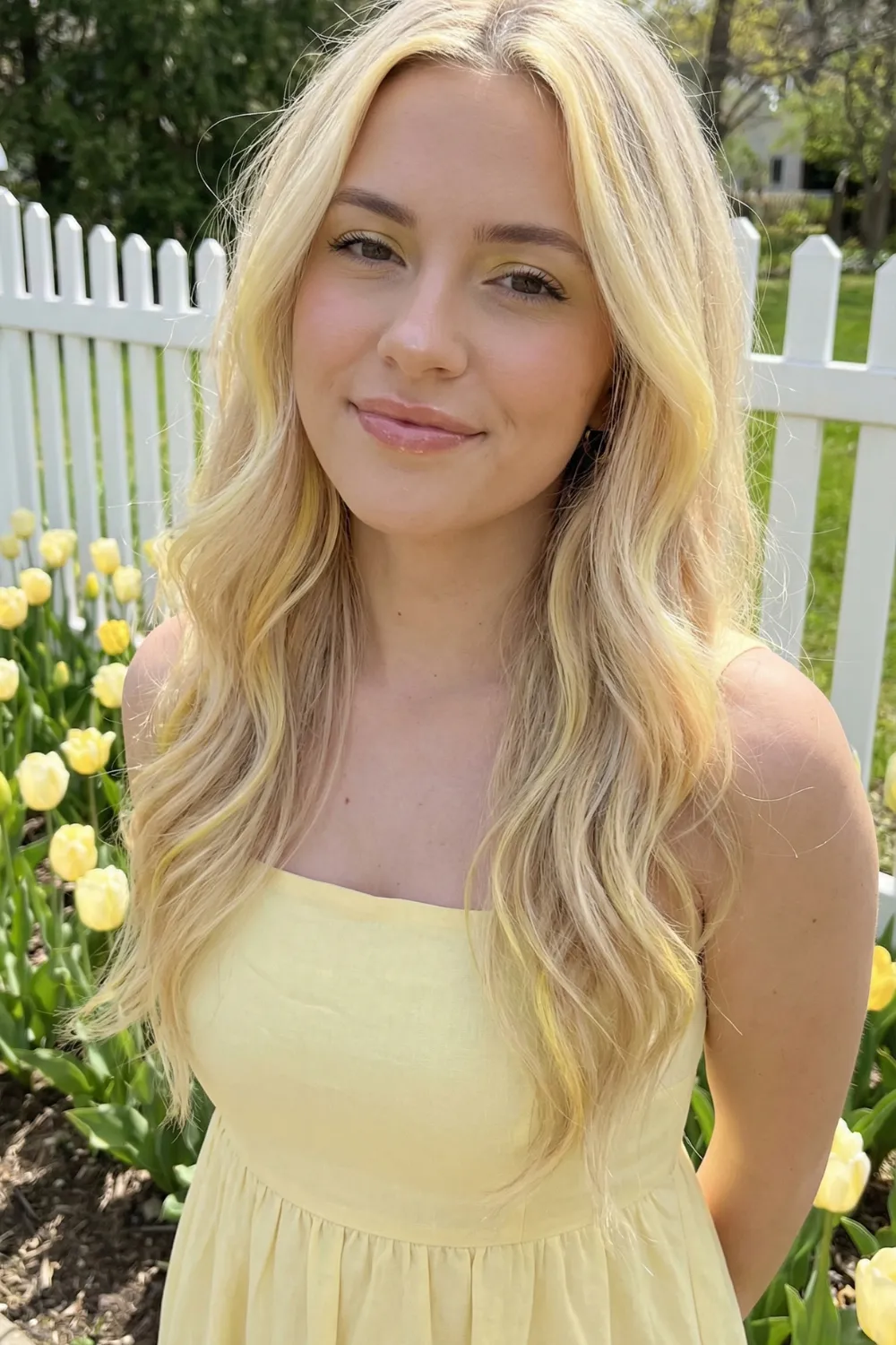 Woman with long buttercream blonde wavy hair and soft yellow highlights