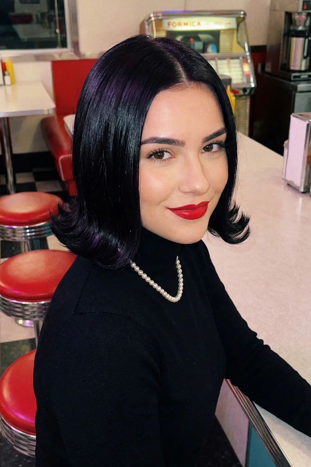 Woman with jet black classic pageboy bob and rolled under ends
