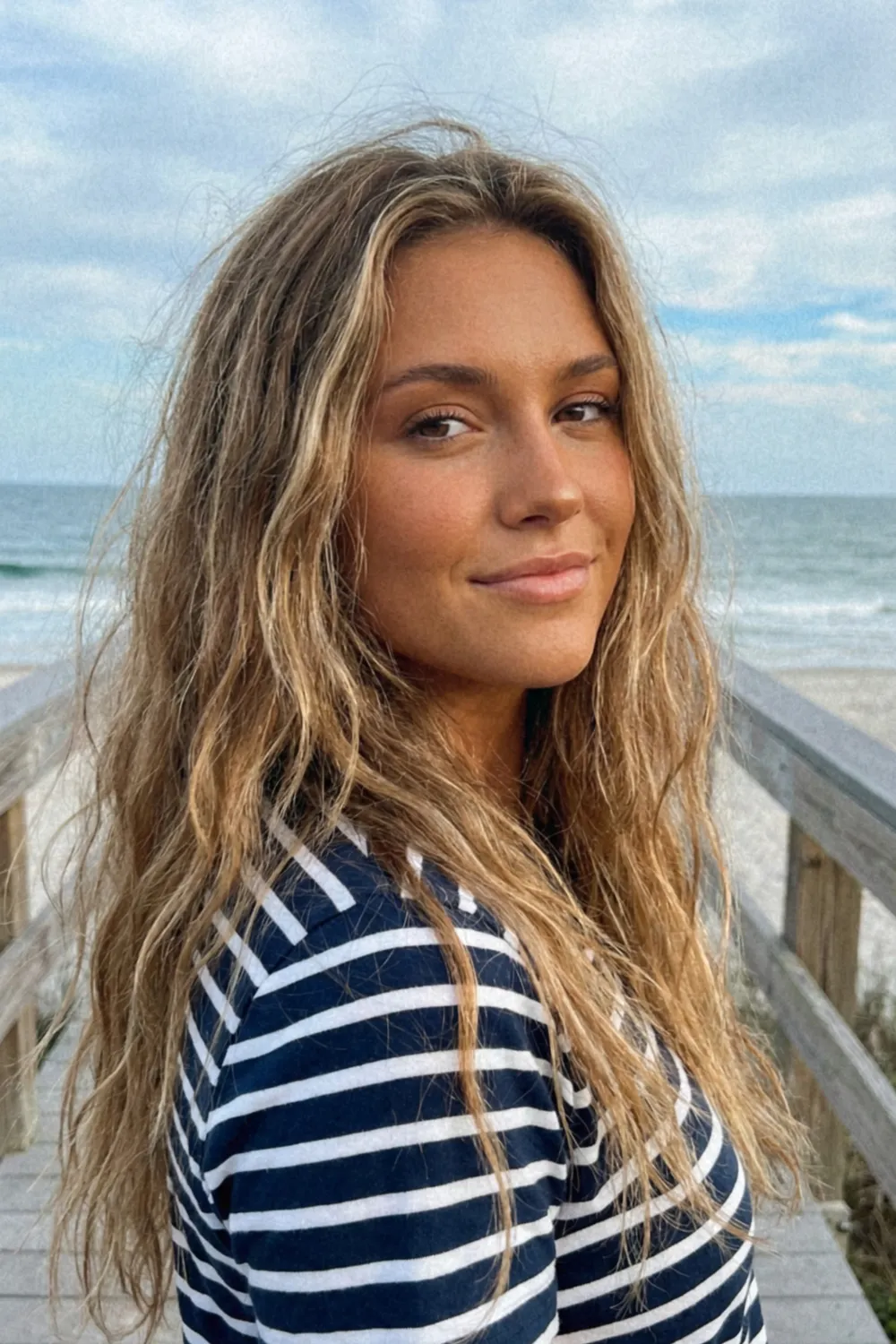 Woman with long dirty blonde beach waves and sun kissed highlights