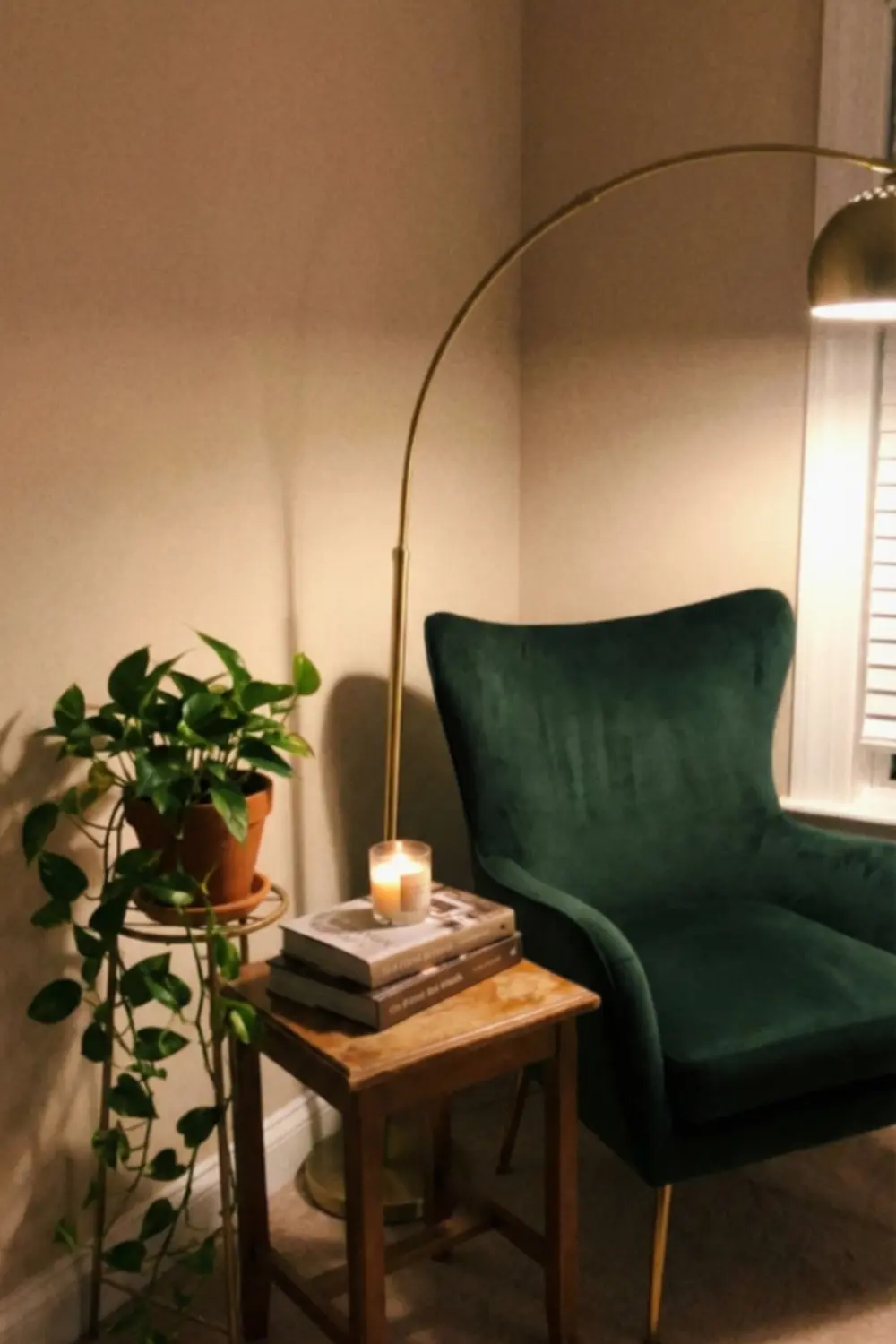 Glam empty corner decor with green velvet chair brass floor lamp and trailing plant