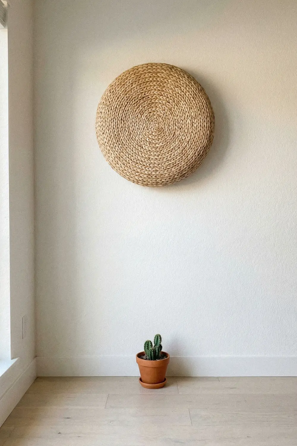 Minimal empty corner decor with round seagrass wall hanging and small cactus pot