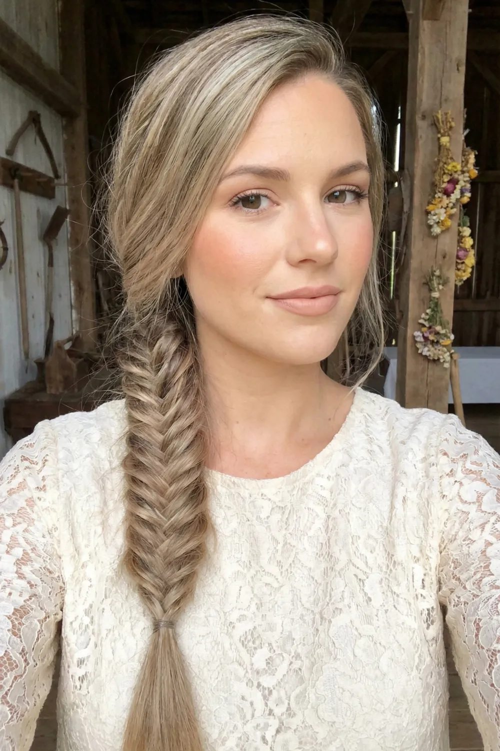 Woman with long sandy beige blonde hair and ash highlights in fishtail braid
