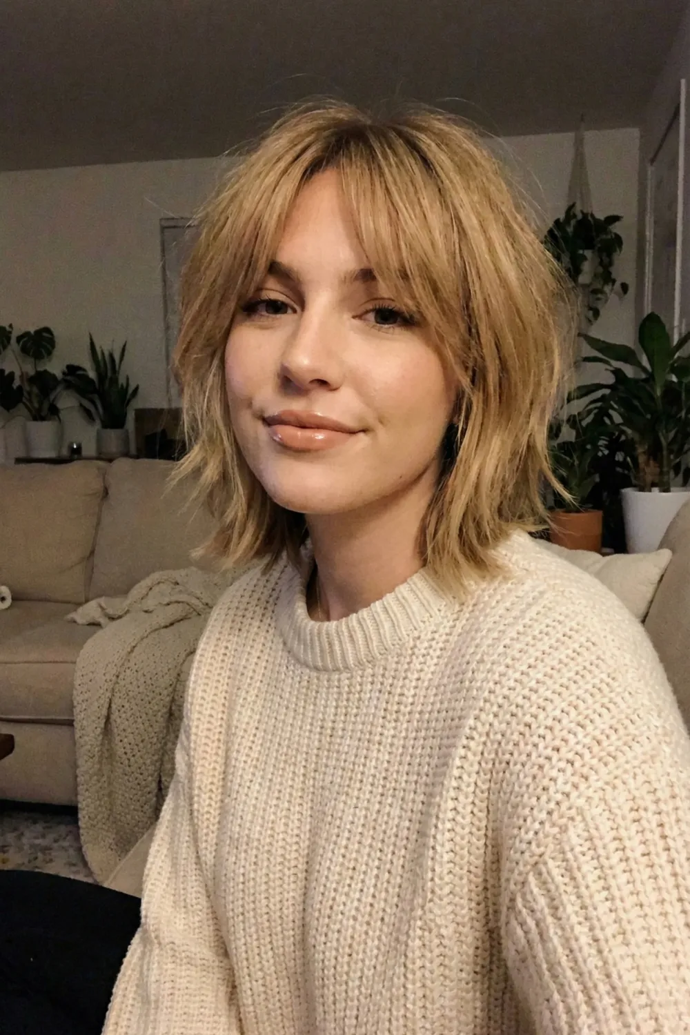 Woman with shaggy honey blonde layered bob and curtain bangs