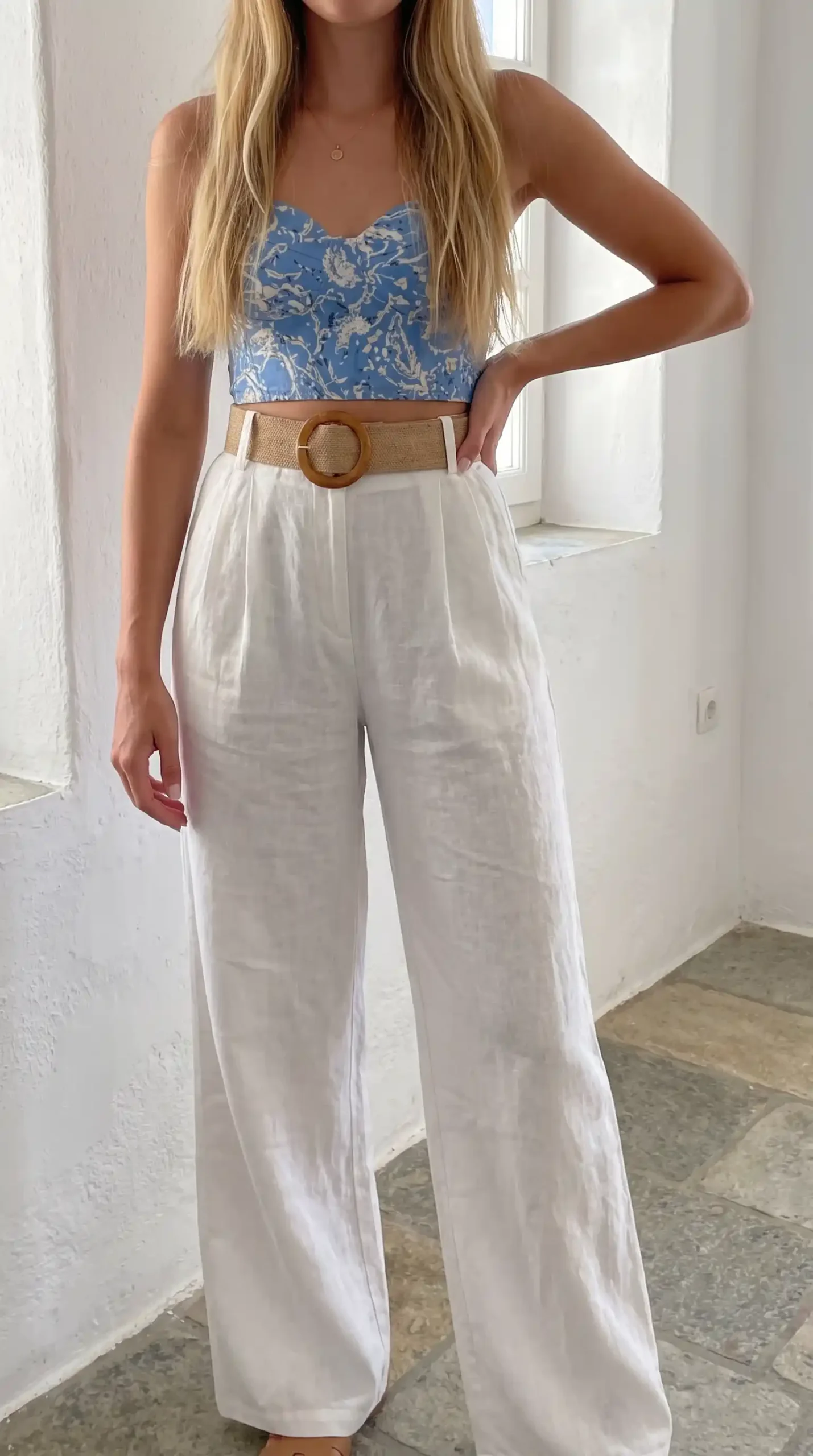 Woman wearing blue floral embroidered corset top with white wide-leg pants in Italy