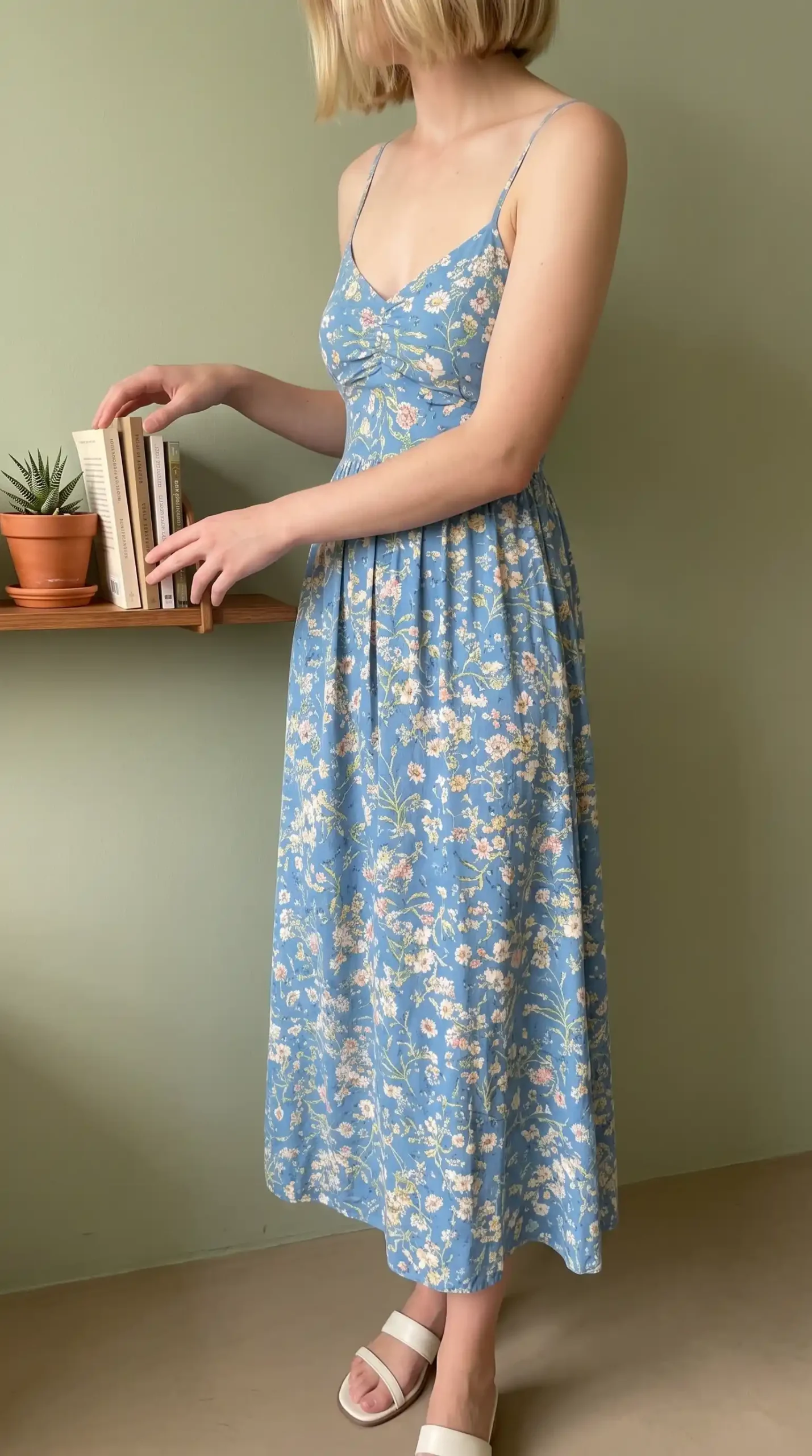 Woman wearing blue floral midi dress with ruched bodice and spaghetti straps
