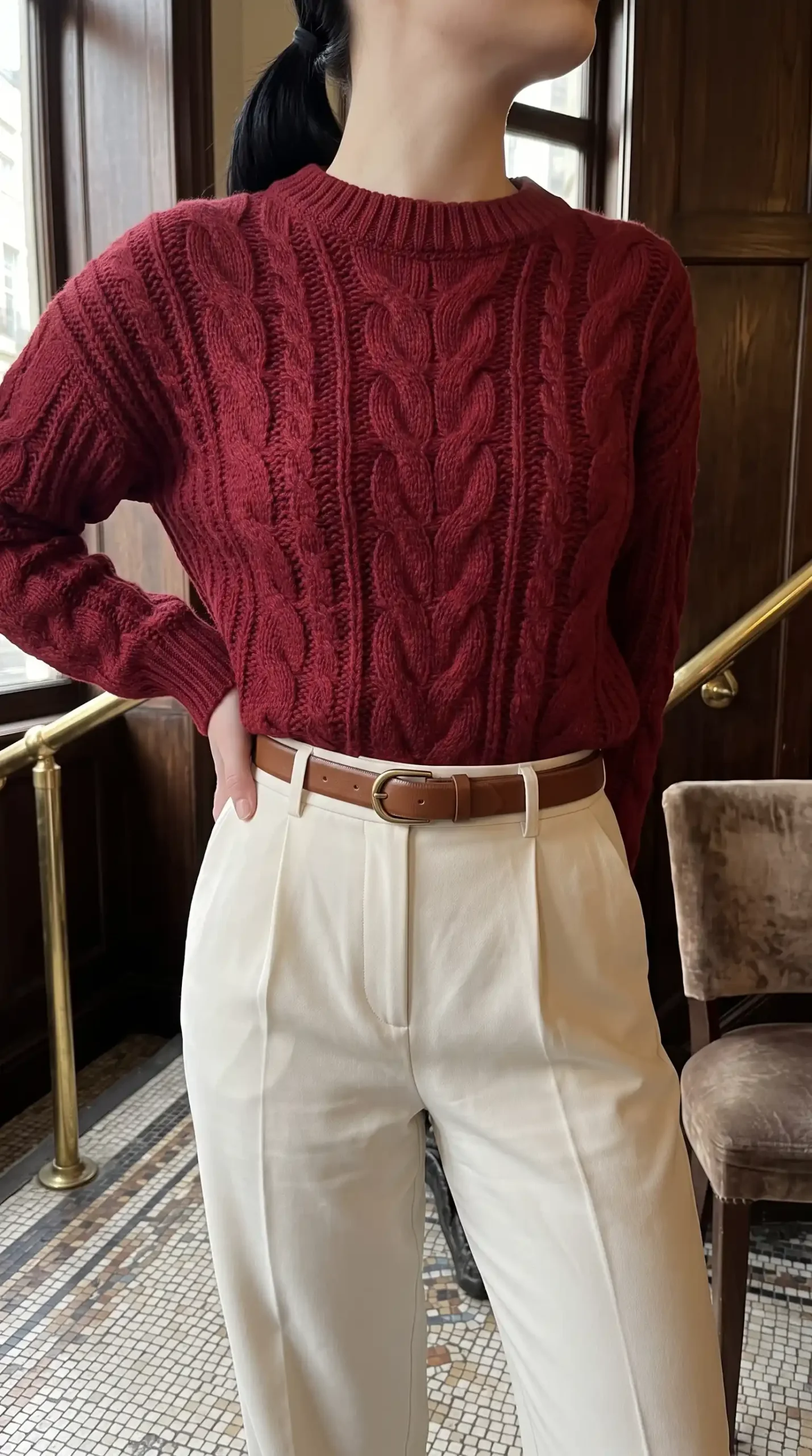 Woman wearing burgundy cable knit sweater with cream wide-leg pants and brown belt