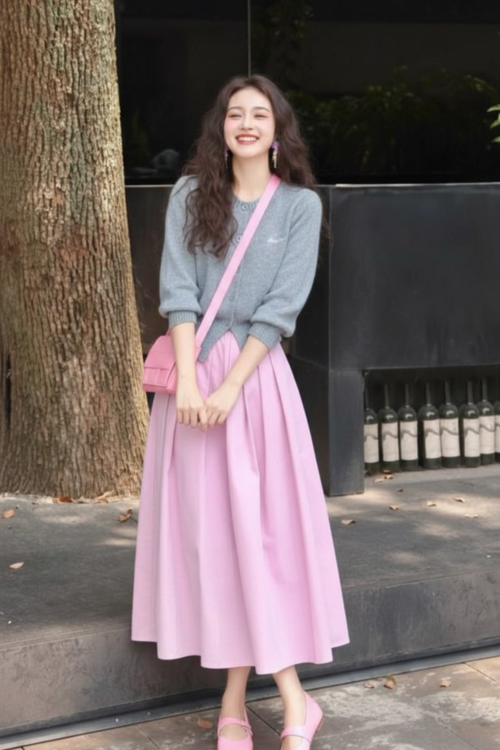 Woman wearing a grey long-sleeved top with a pink skirt, pink shoes, and a pink shoulder bag outdoors