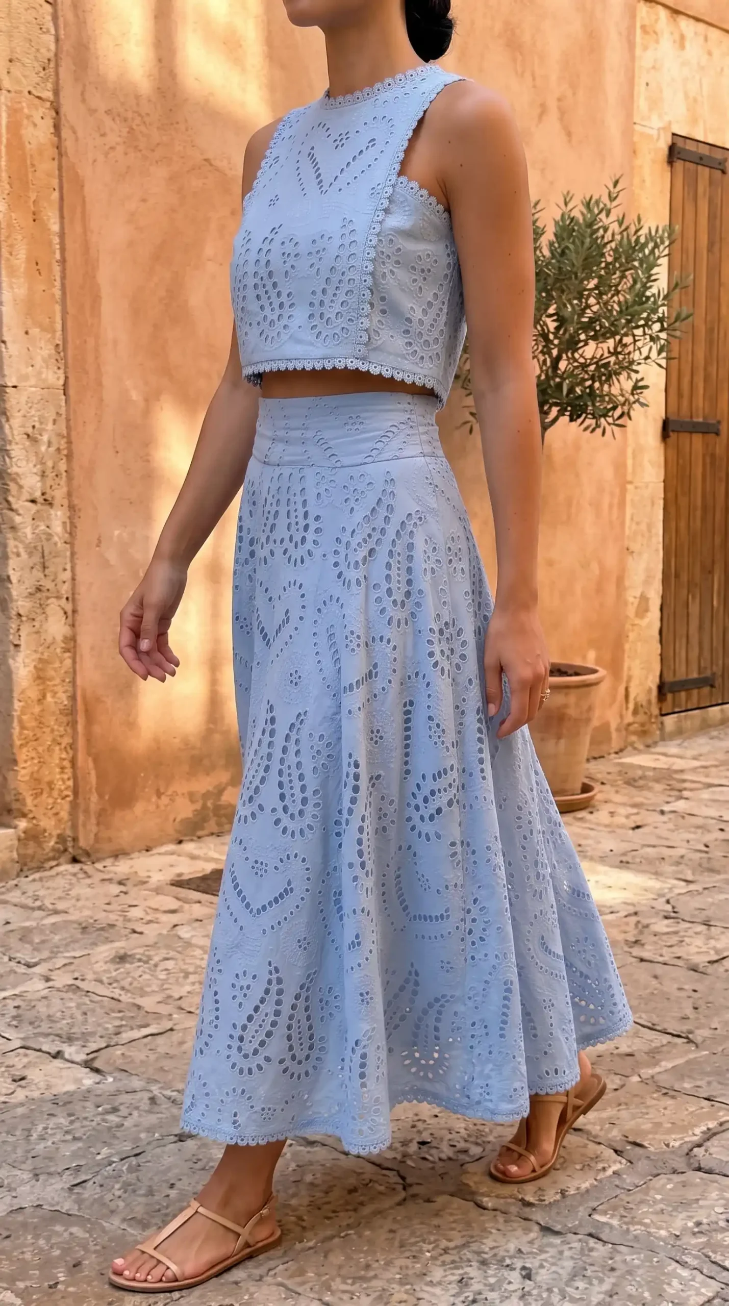 Woman wearing light blue eyelet crop top with matching midi skirt set in tropical setting