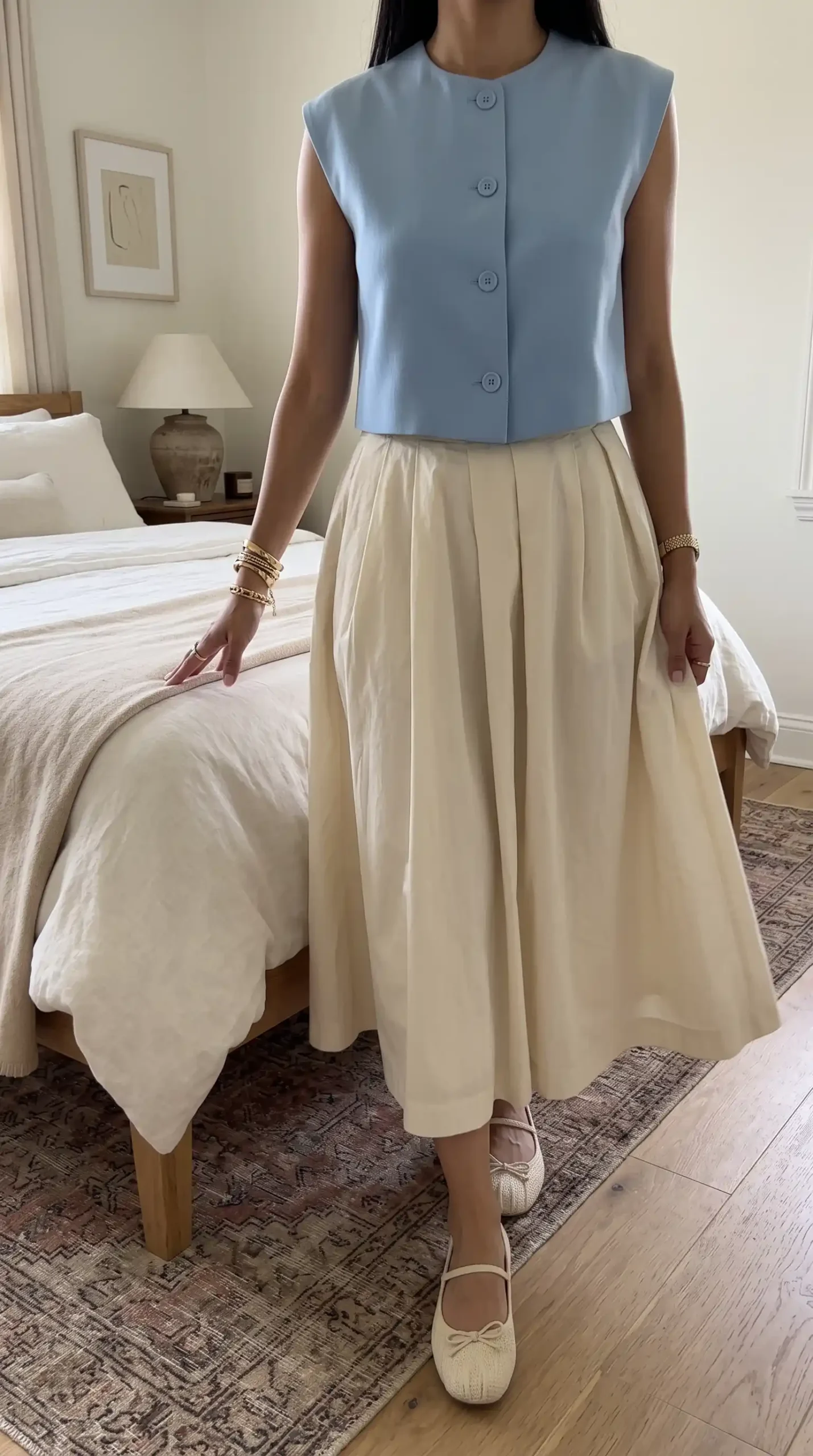 Woman wearing light blue button-front sleeveless top with cream full midi skirt