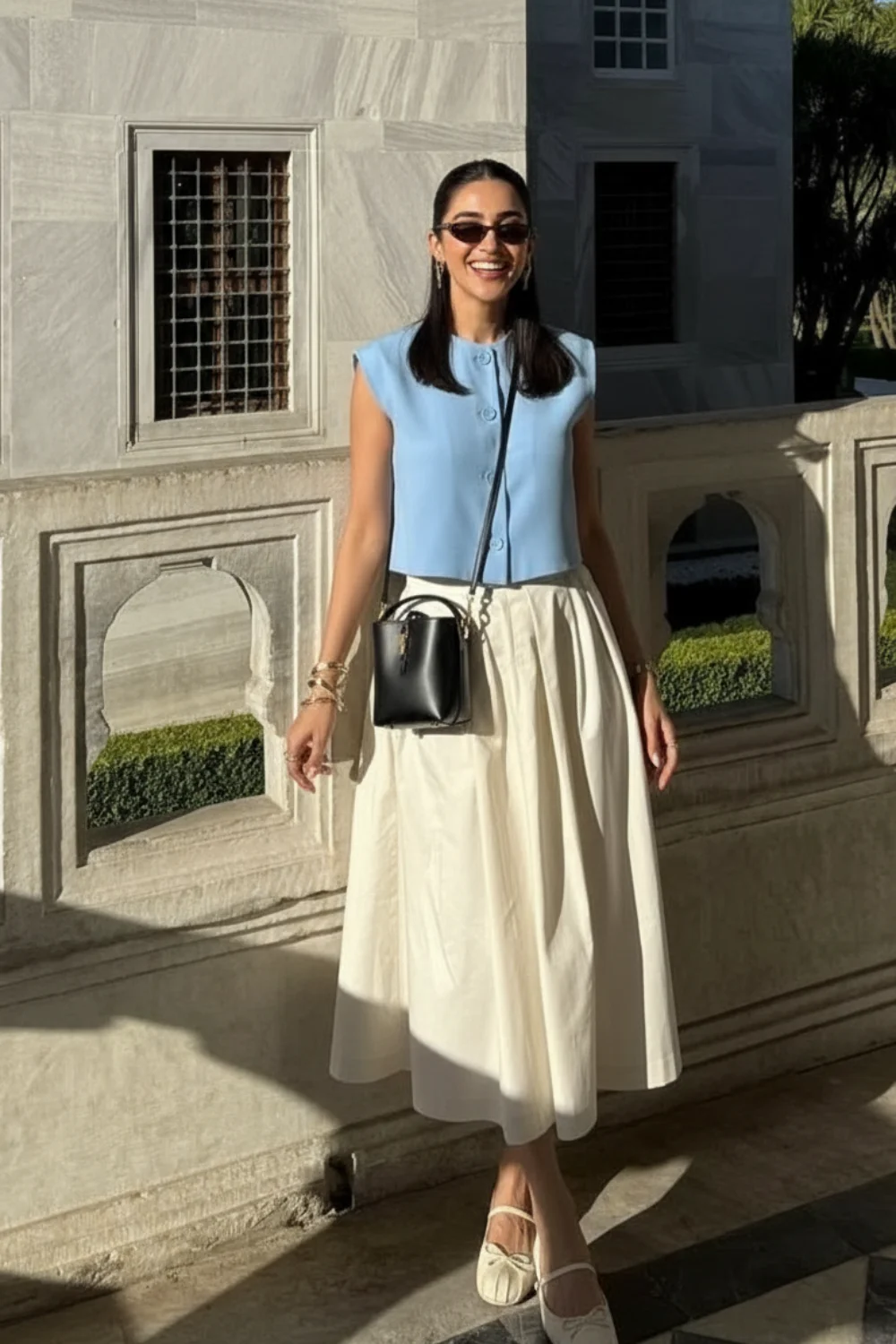 Woman wearing light blue button-front sleeveless top with cream full midi skirt