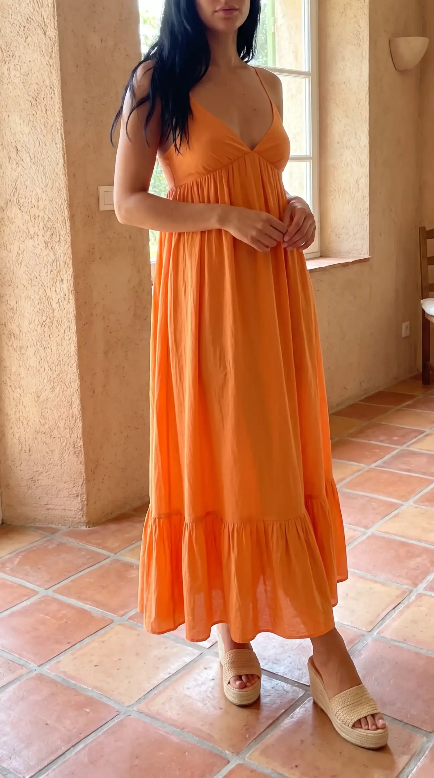 Woman wearing orange spaghetti strap v neck tiered ruffle hem maxi dress