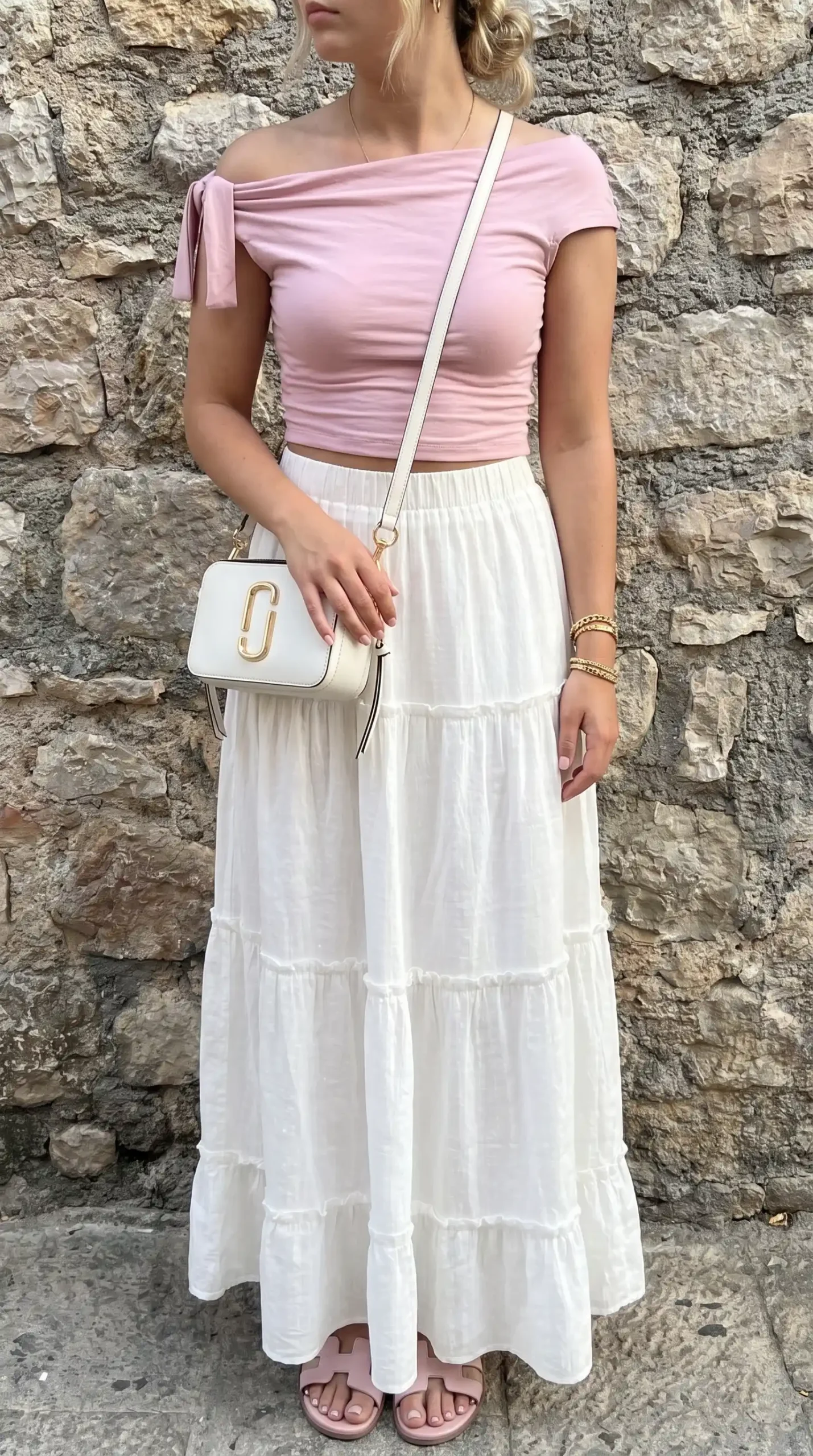 Woman wearing a light pink off-shoulder top with a white tiered skirt