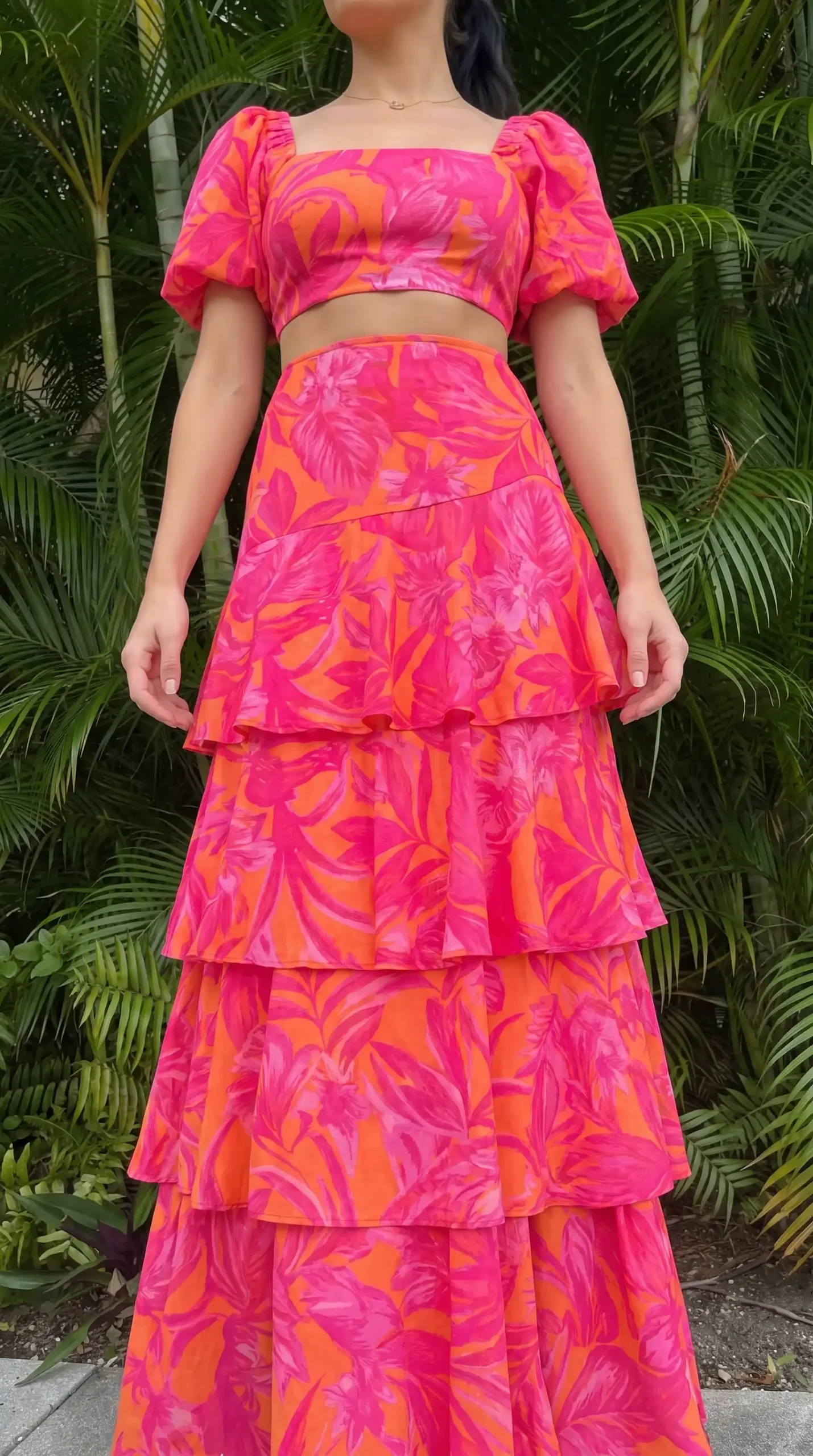 Woman wearing pink orange tropical print puff sleeve crop top and tiered maxi skirt co-ord