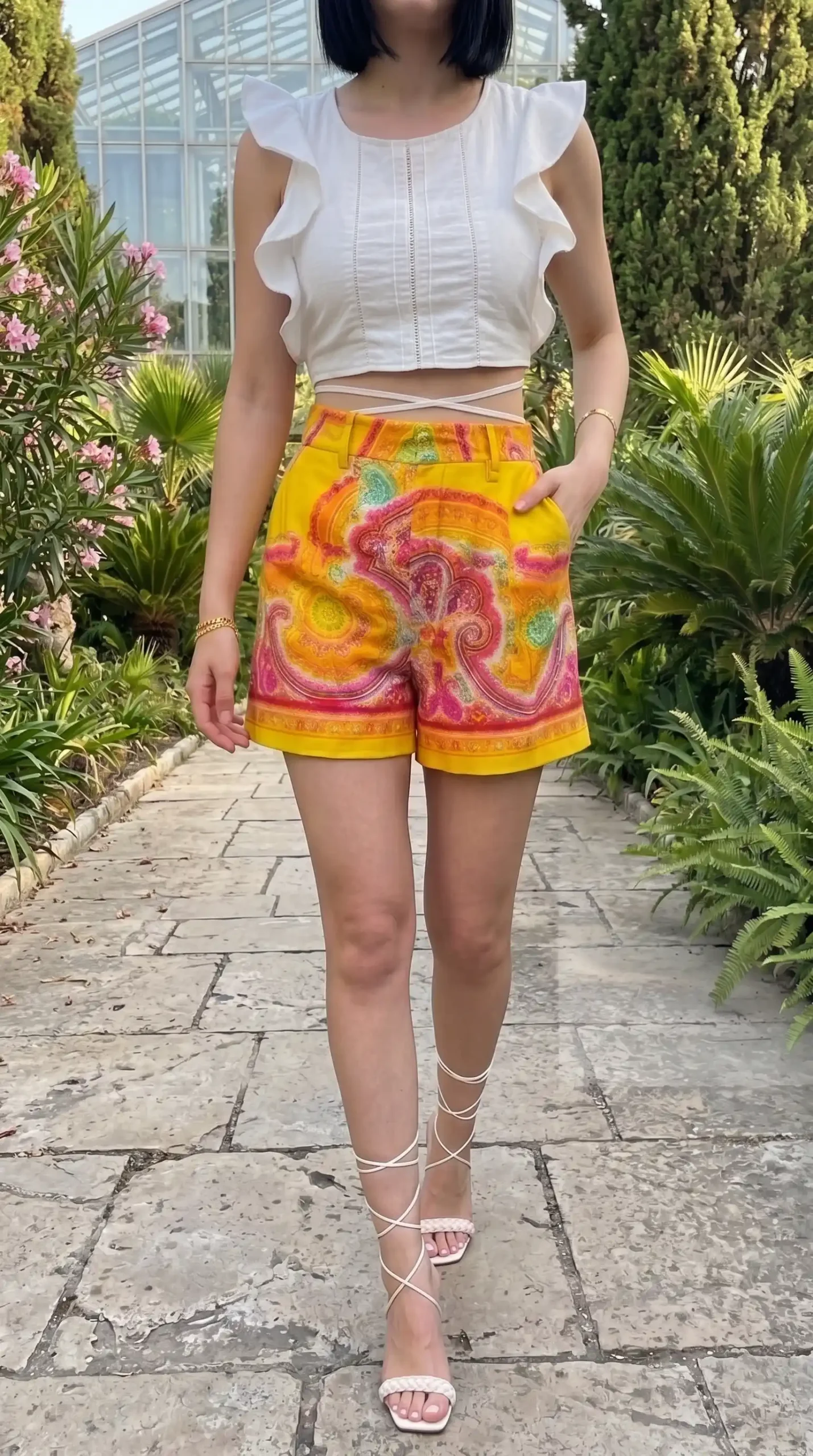 Woman wearing white ruffle crop top with yellow paisley print high waist shorts