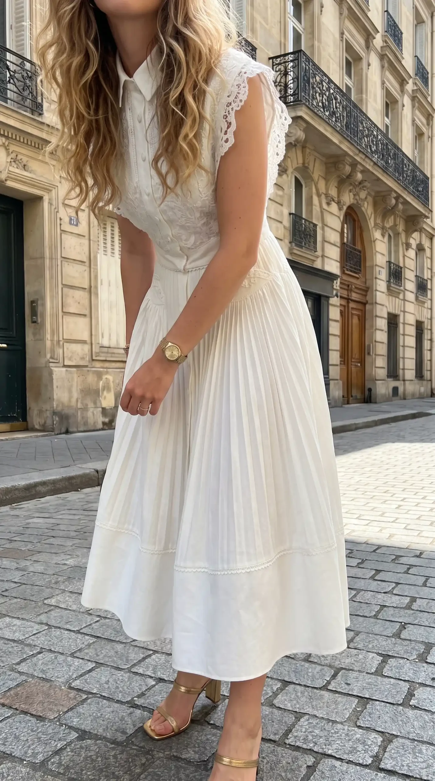Woman wearing white lace midi dress with eyelet bodice and pleated skirt on Paris street