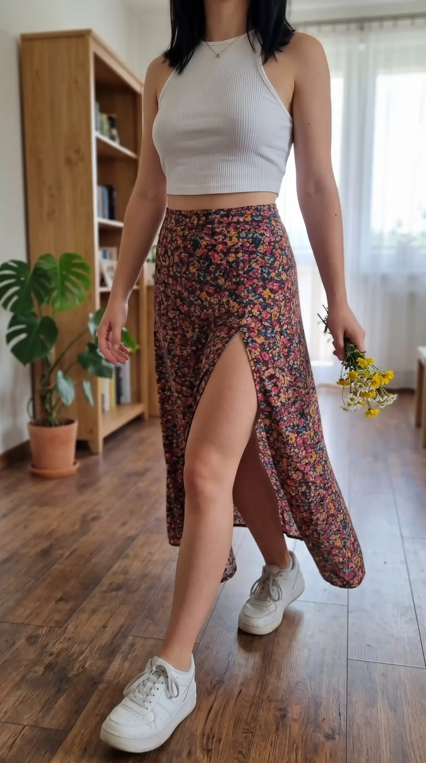 Woman wearing white ribbed halter crop top with dark floral thigh slit maxi skirt