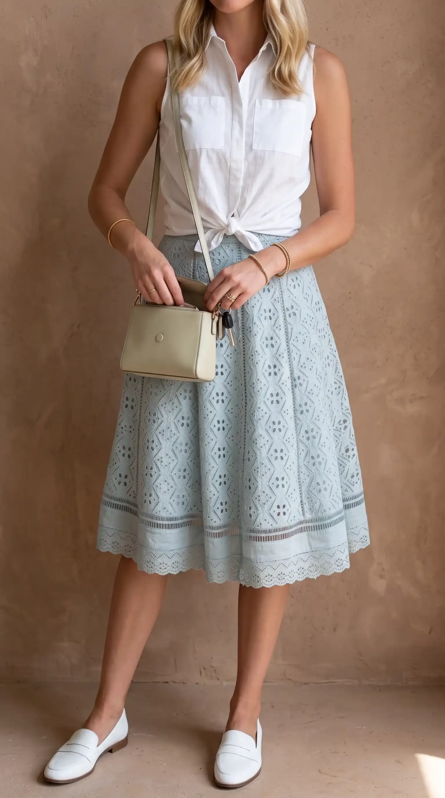 Woman wearing white sleeveless button-up with light blue eyelet midi skirt and white loafers