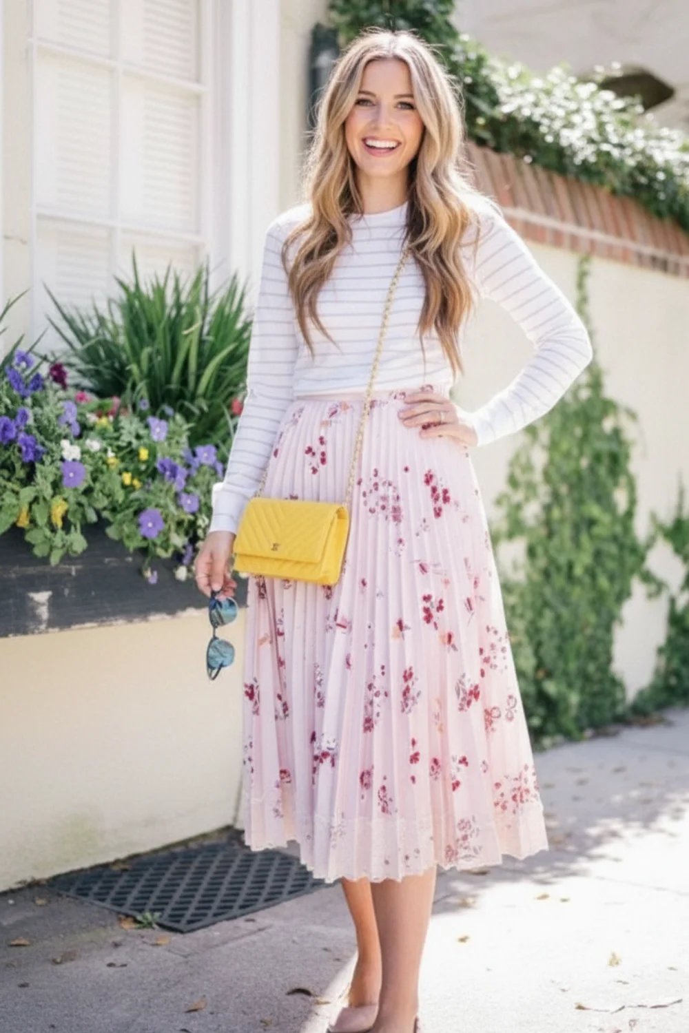 Woman wearing white striped long sleeve top with blush pink floral pleated midi skirt