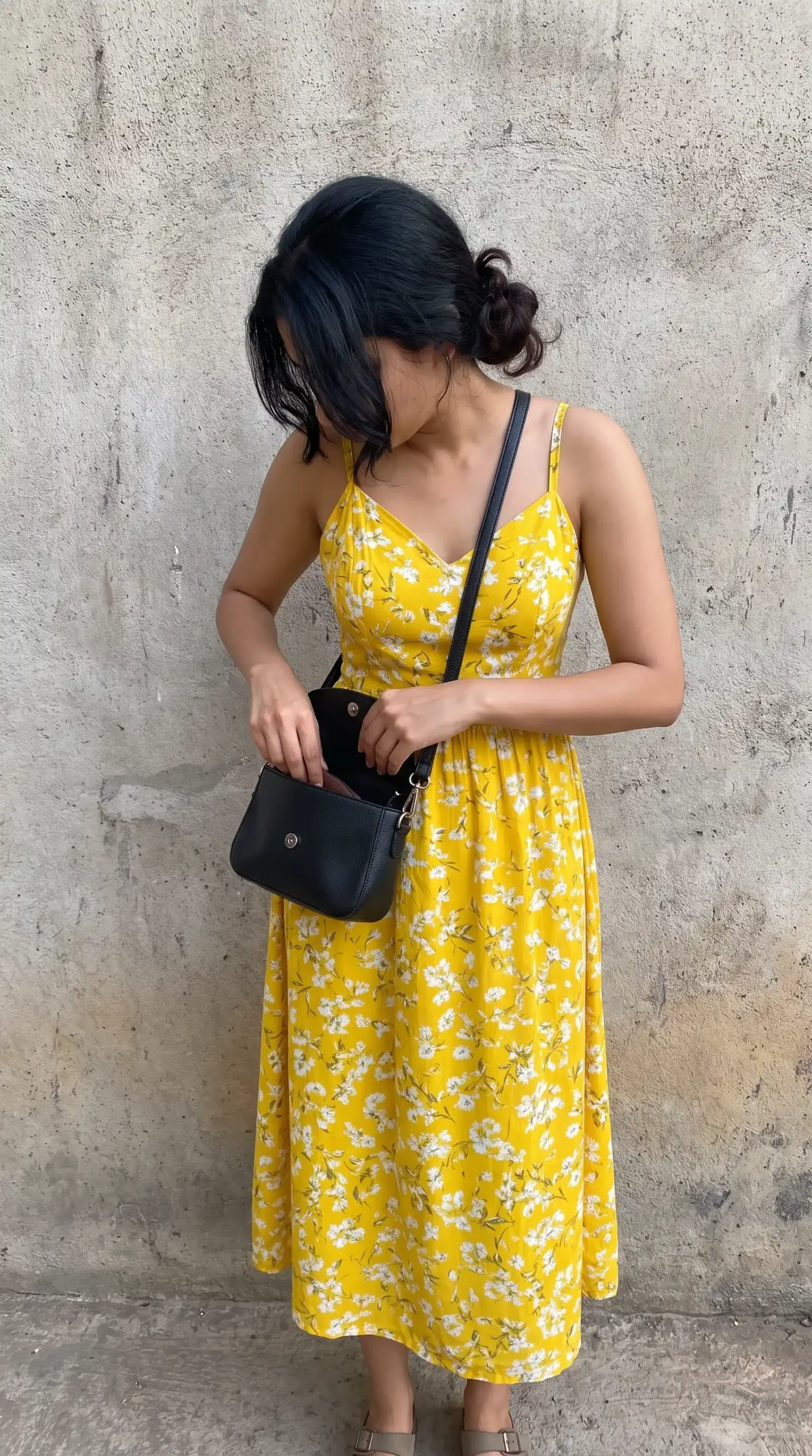 Woman wearing a bright yellow floral dress with thin straps outdoors in a park setting