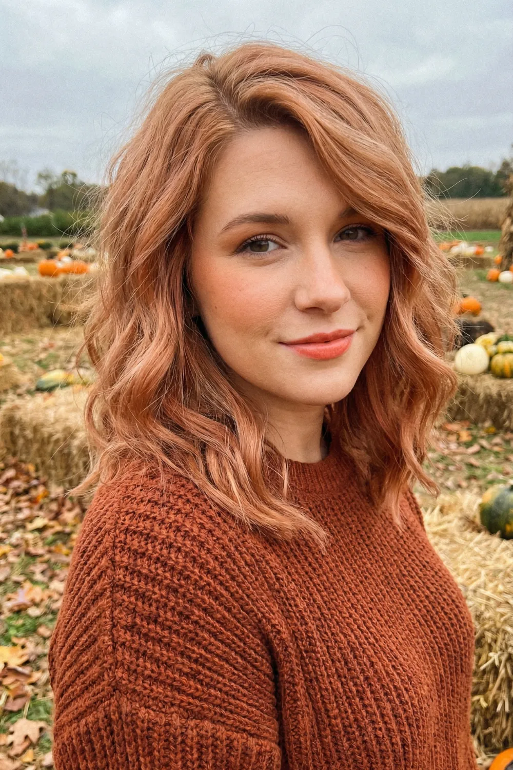 Woman with medium length strawberry blonde hair and rose gold tones
