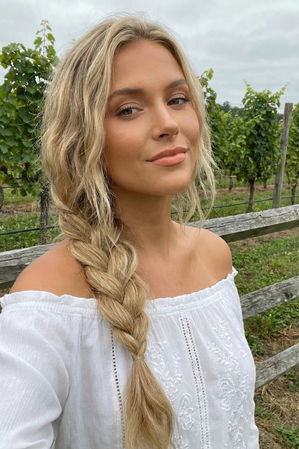 Woman with long wheat blonde hair and golden honey tones in braid