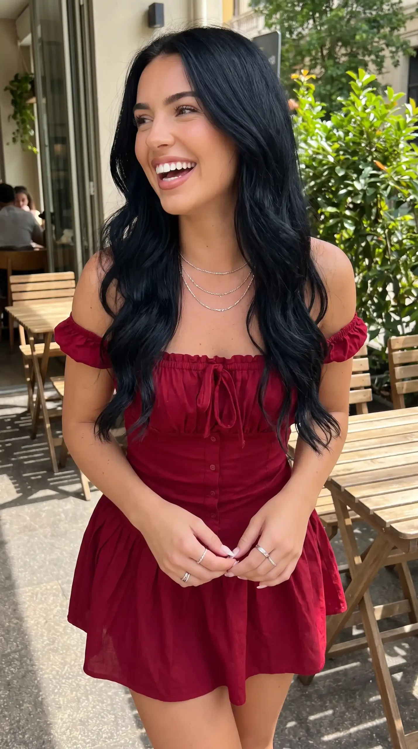 Woman smiling in burgundy off shoulder button front mini dress