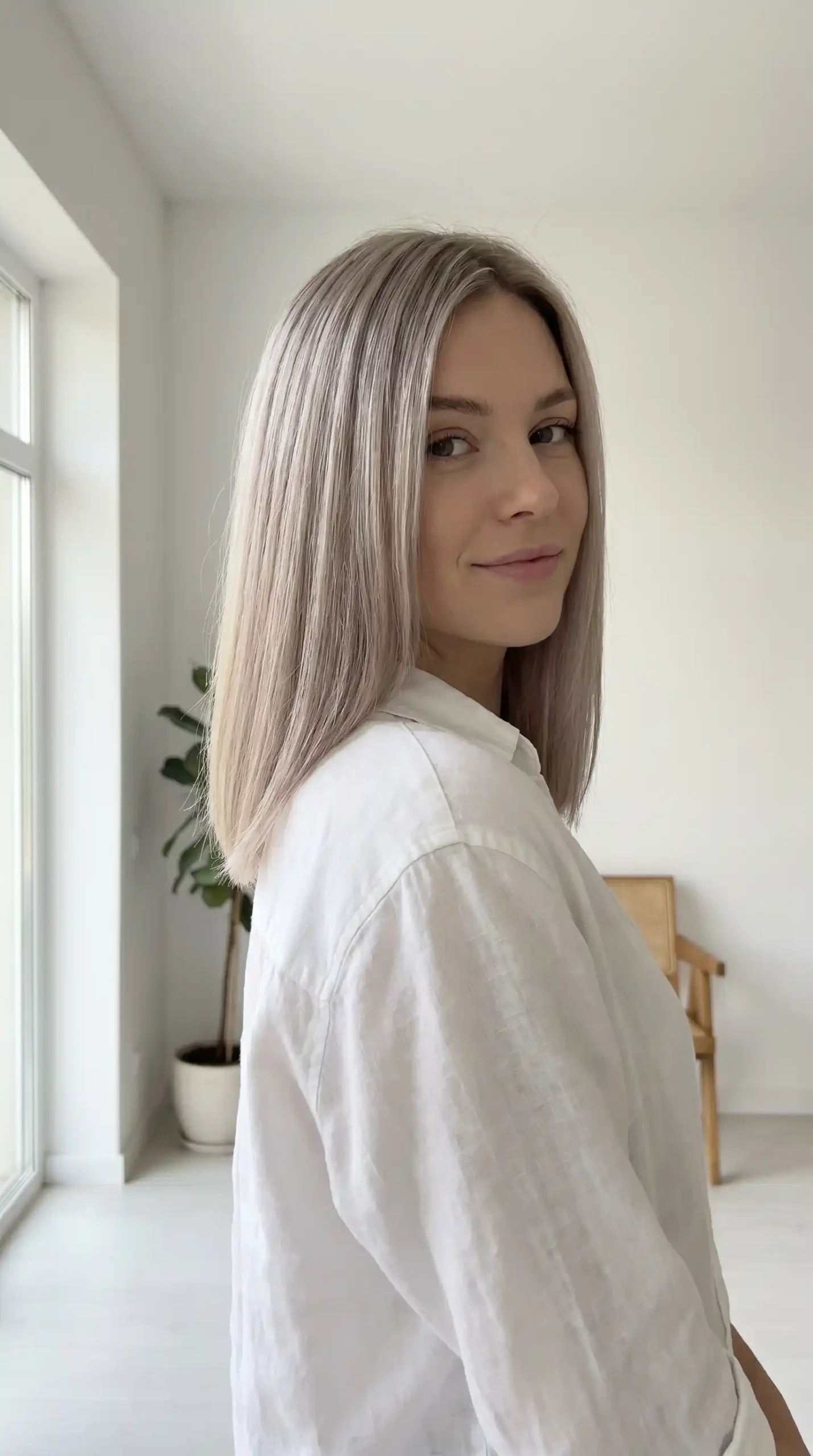 Woman with glossy ash blonde flowing straight hair and side part