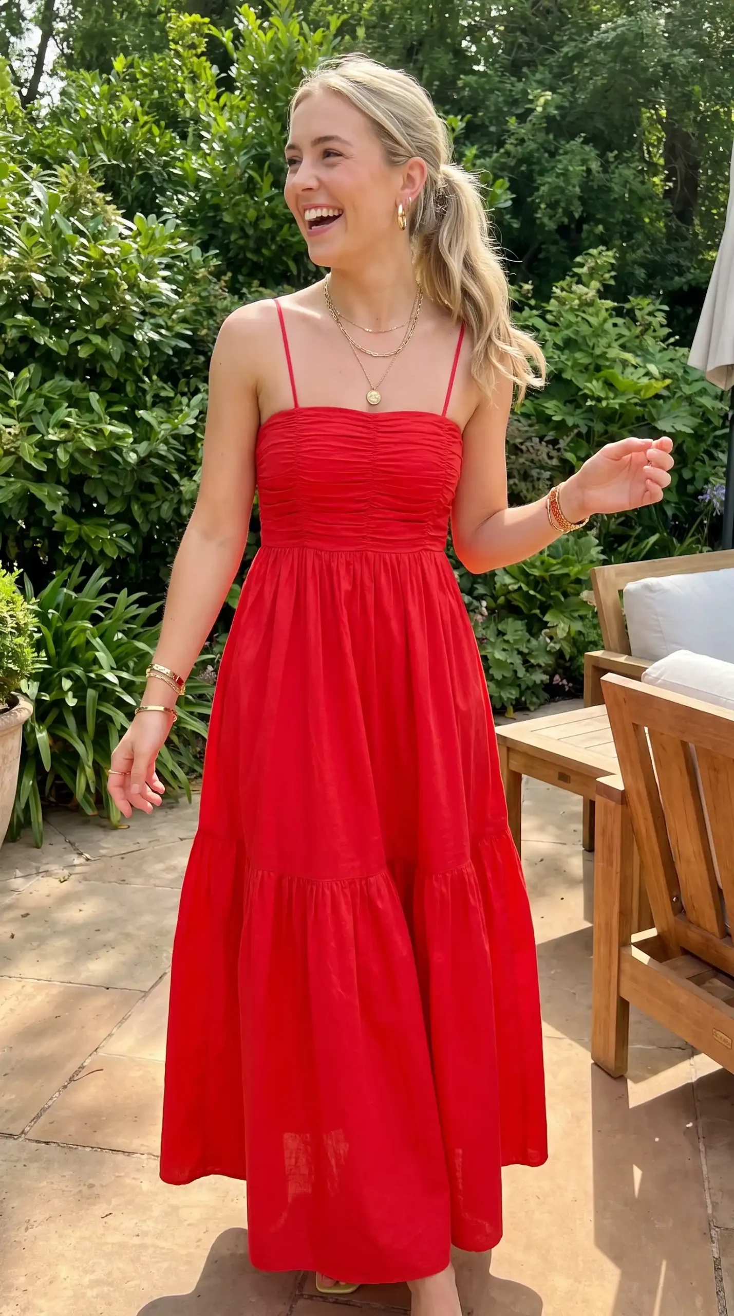 Woman wearing red ruched bodice spaghetti strap tiered midi dress outdoors