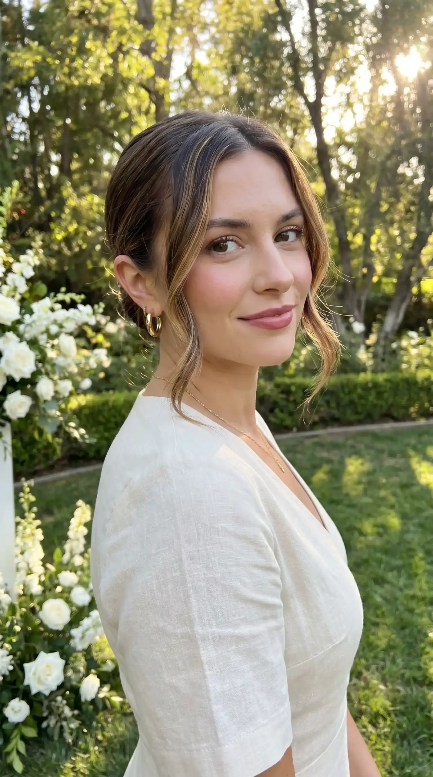 Woman with chestnut brown sleek low bun and soft face framing pieces