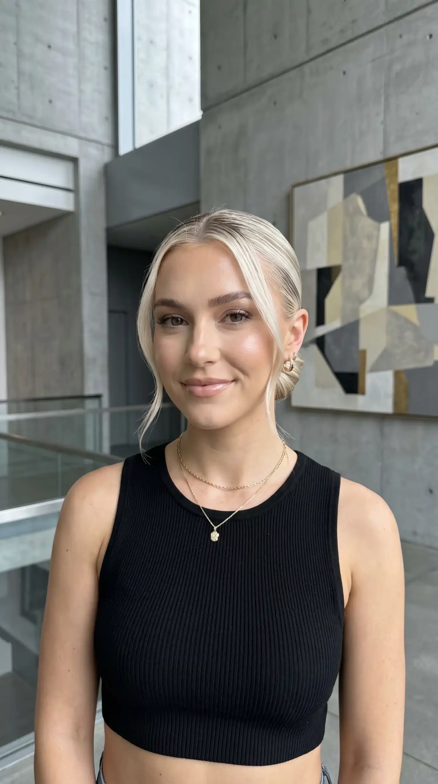Woman with platinum blonde slicked back low bun and face framing pieces