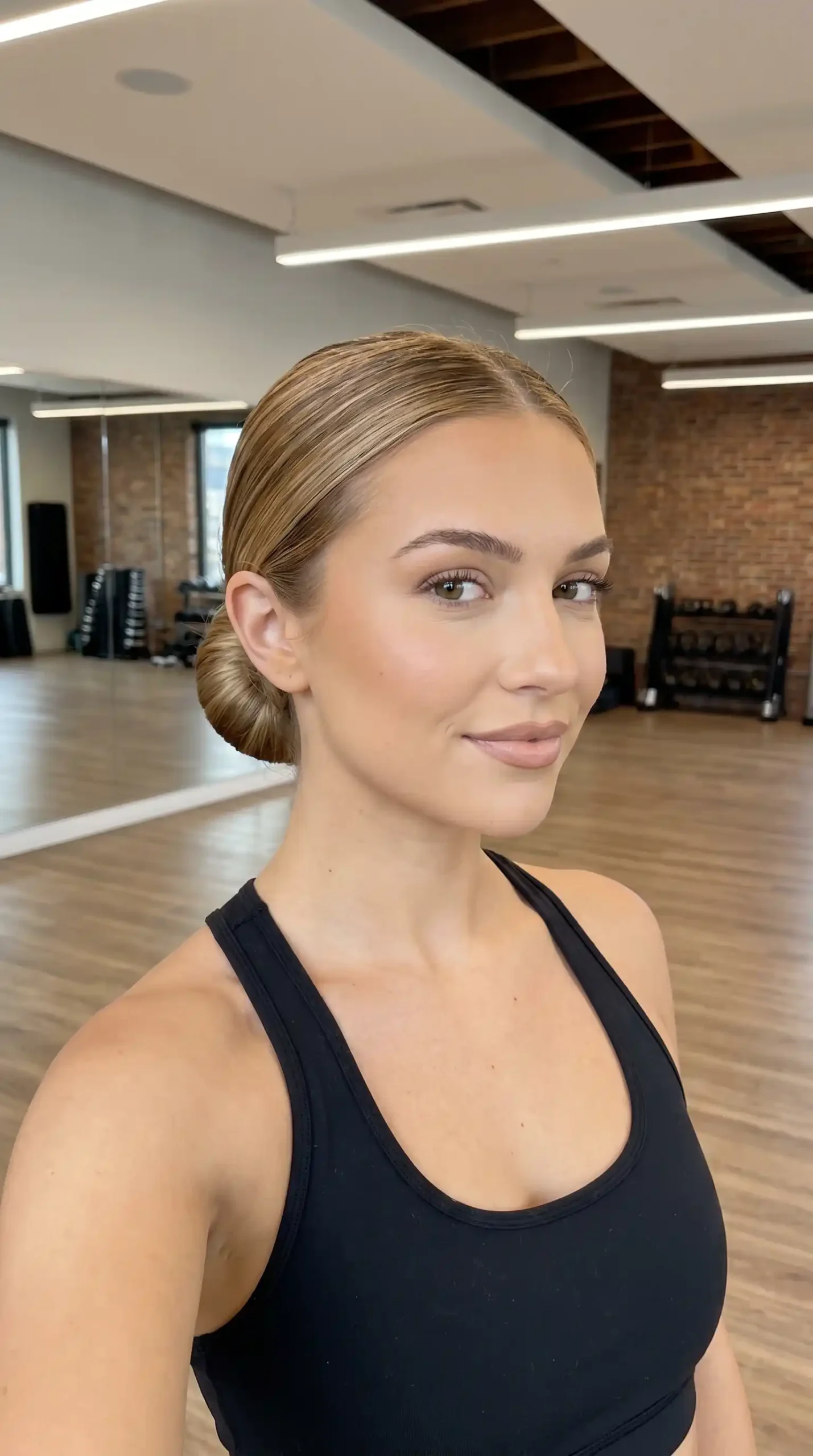Woman with honey blonde slicked back low bun hairstyle