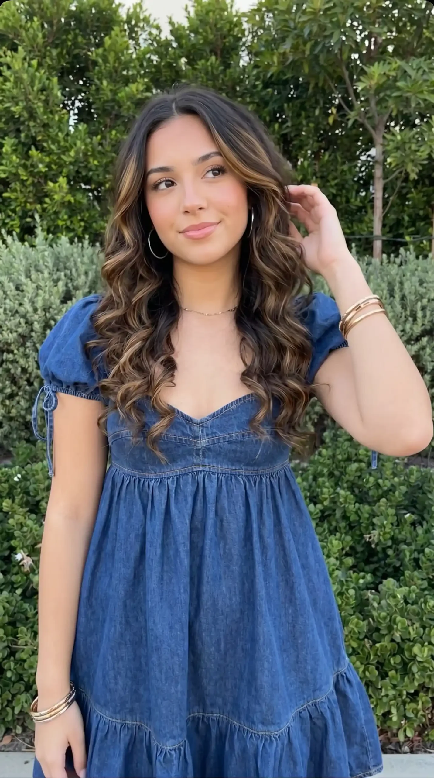 Woman wearing blue denim mini dress with puff sleeves in garden setting