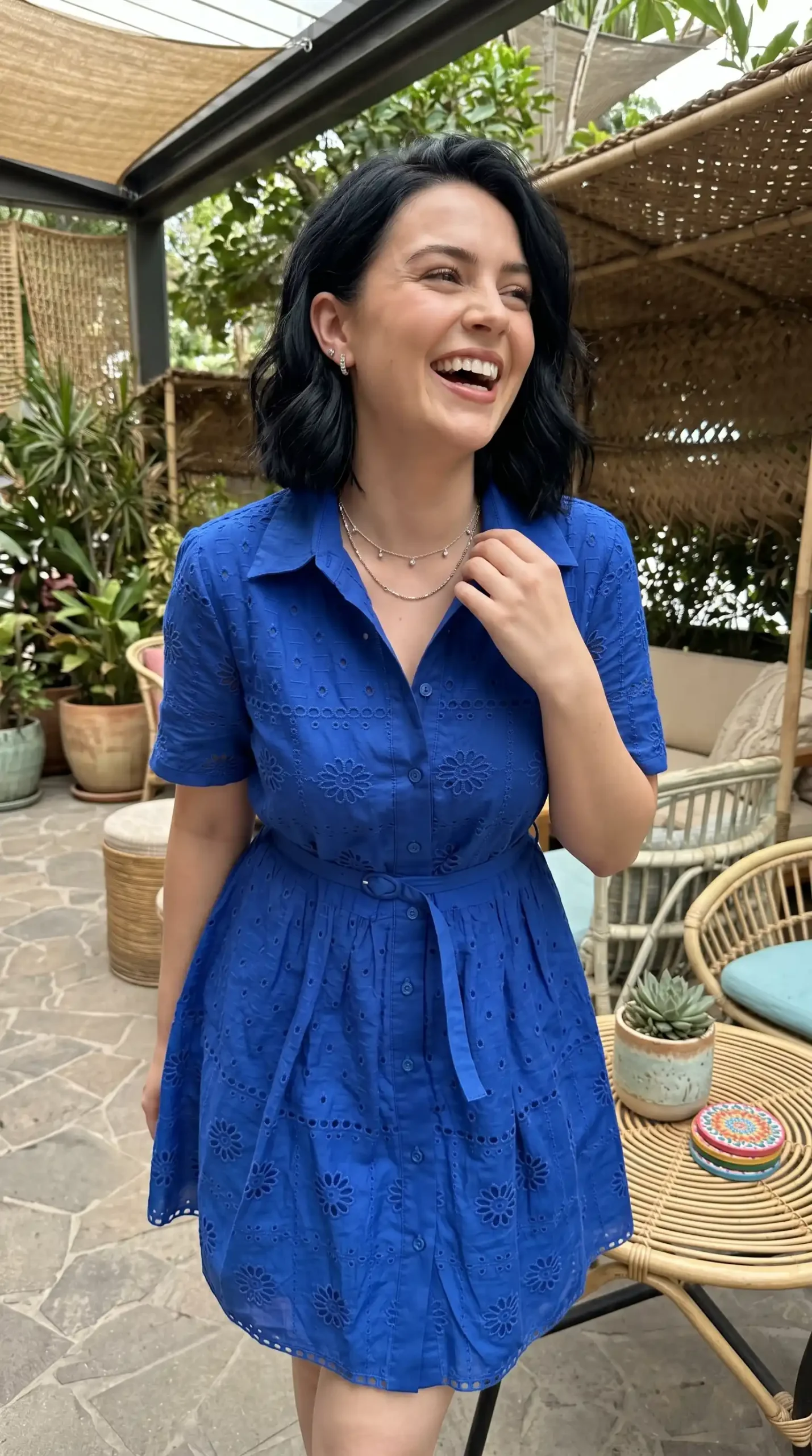 Woman wearing cobalt blue eyelet lace collared short sleeve belted mini dress outdoors in summer