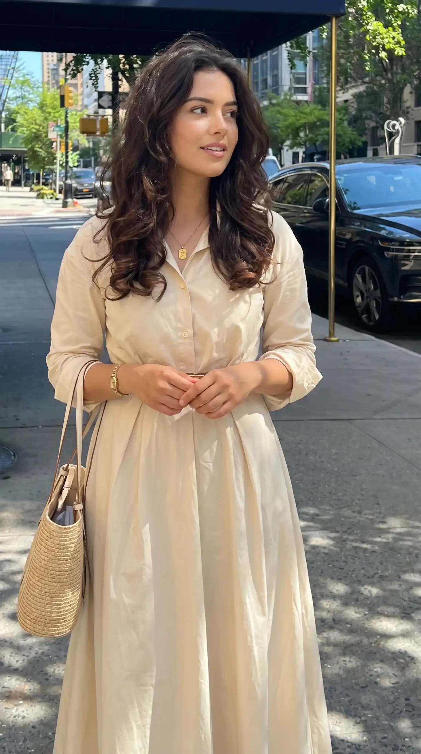 Woman wearing cream beige collared shirt midi dress with straw bag on city street in summer