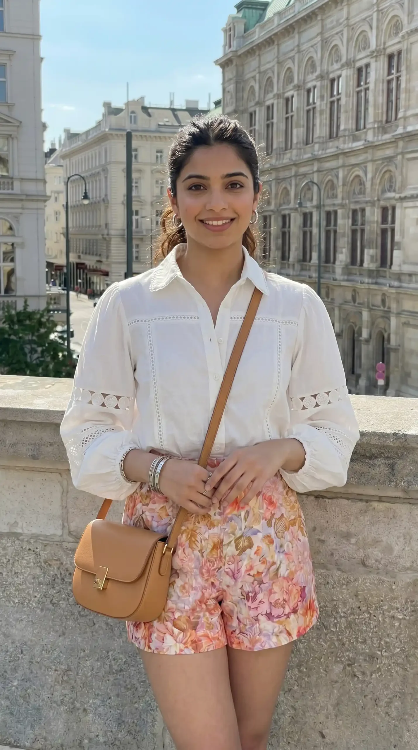 Woman wearing cream eyelet shirt with pink orange floral mini skirt in European city