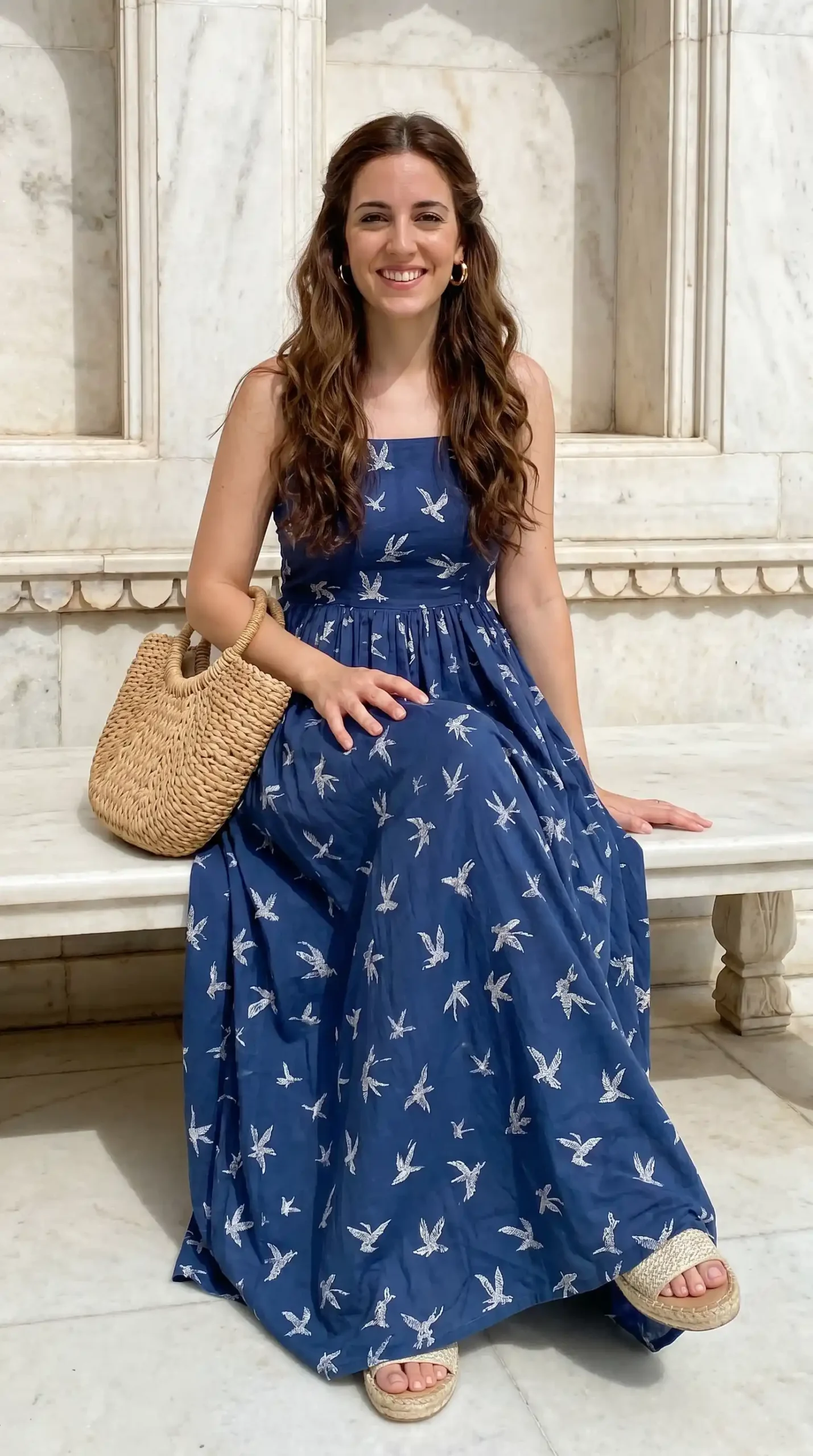 Woman wearing navy blue bird print strappy square neck maxi dress with wicker bag and espadrilles