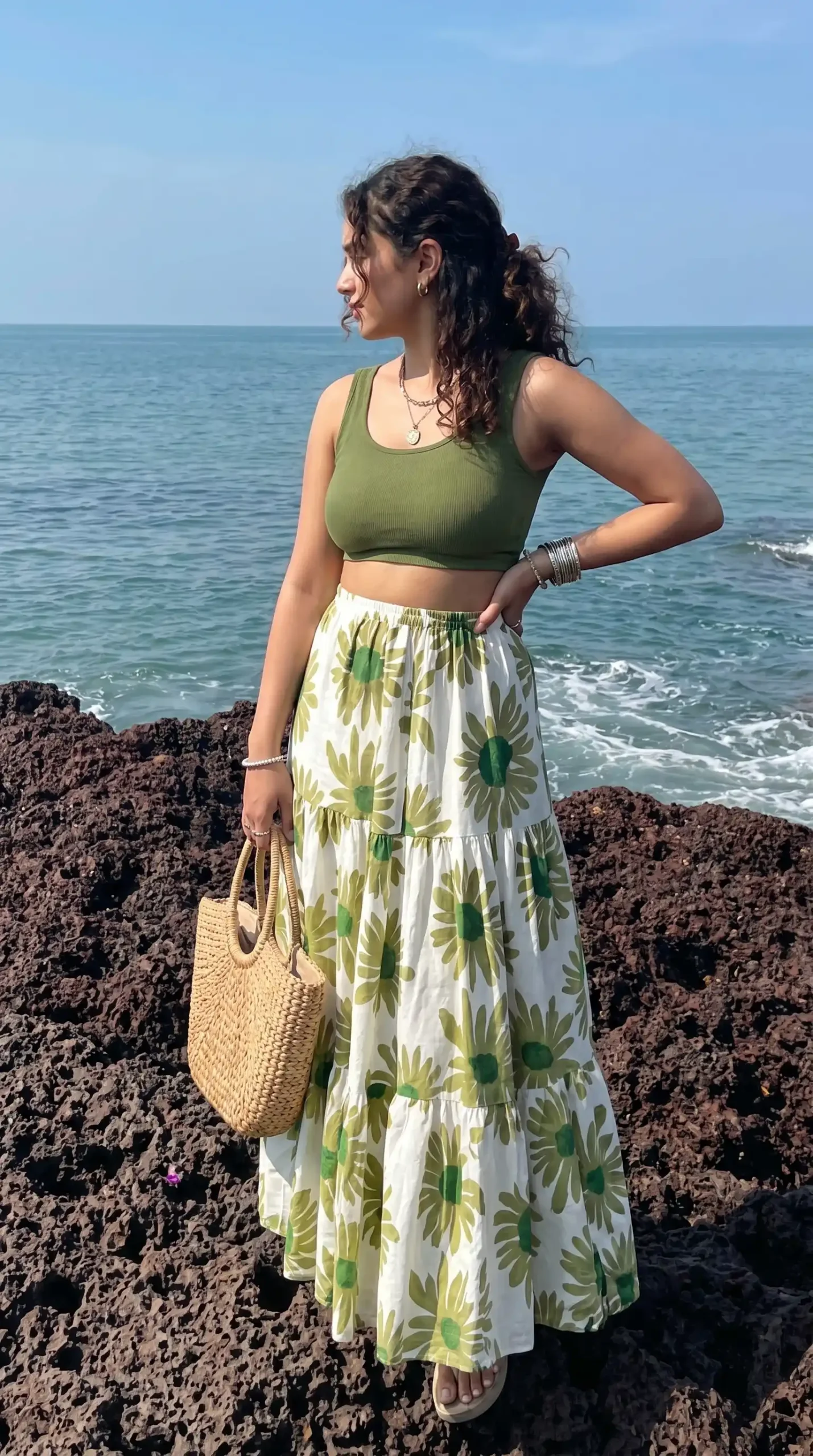 Woman wearing olive green crop top with white sunflower print maxi skirt at the beach