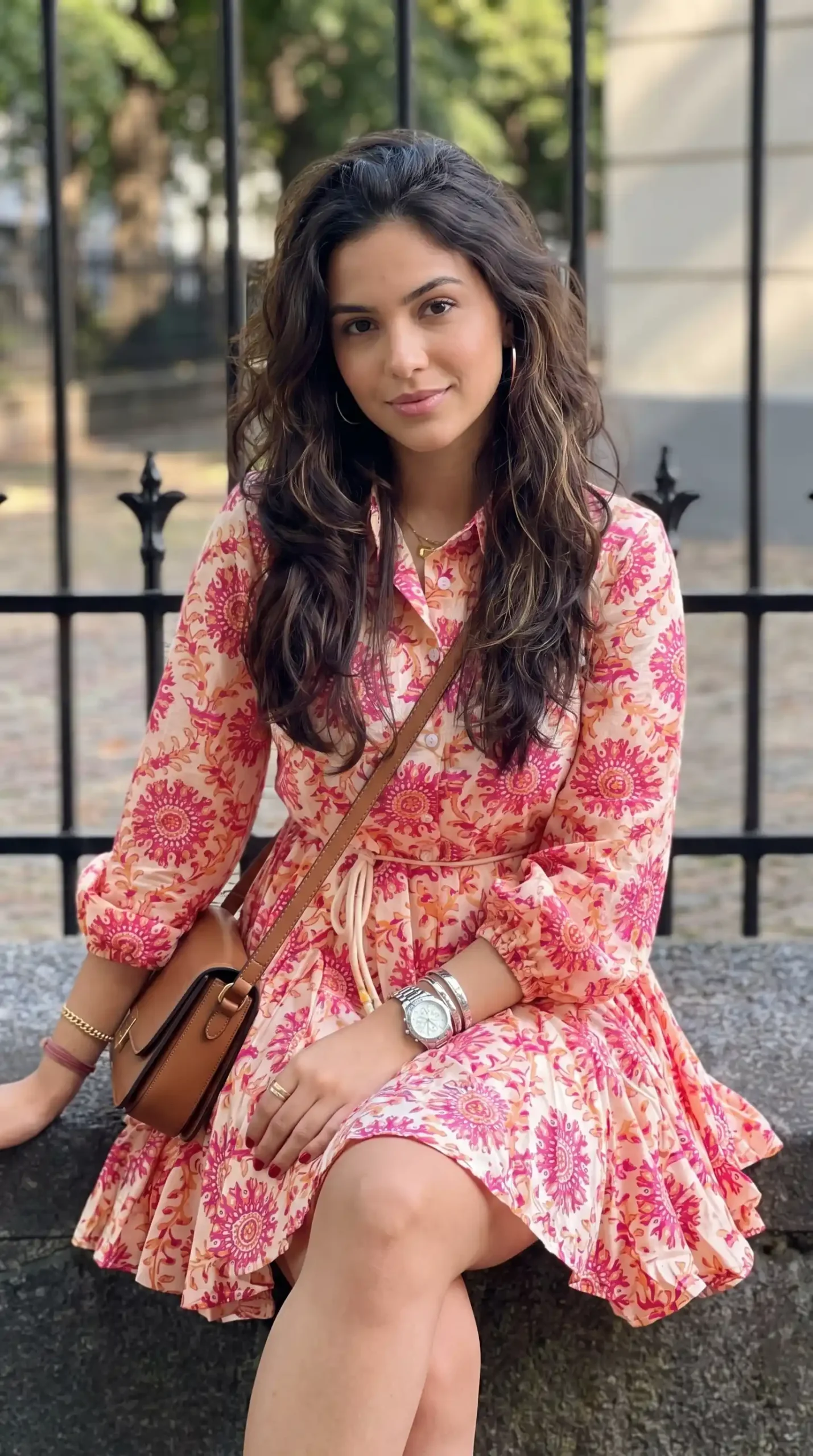 Woman wearing peach and pink medallion print long sleeve shirt mini dress with tan crossbody bag outdoors