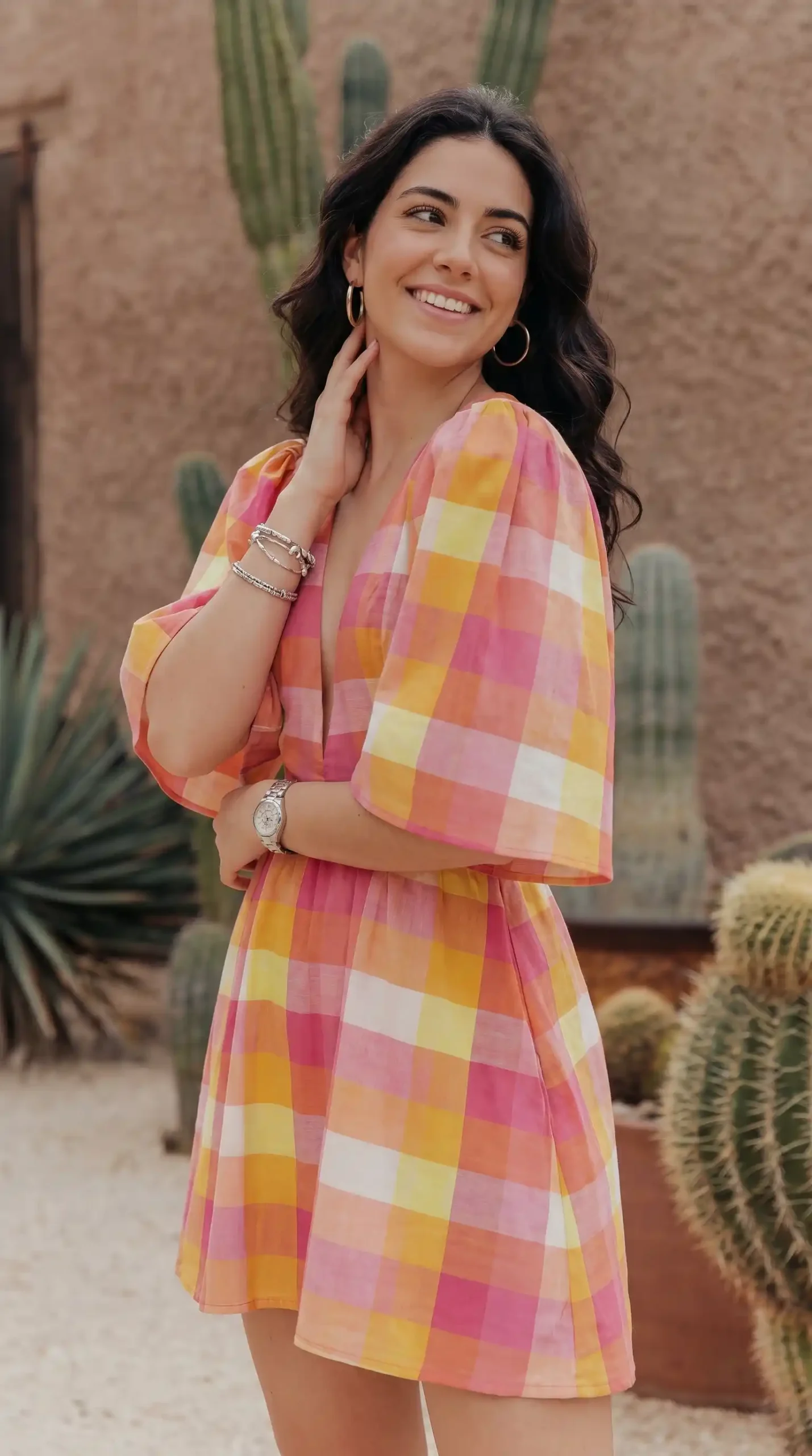 Woman wearing multicolor plaid mini dress in desert setting with cacti