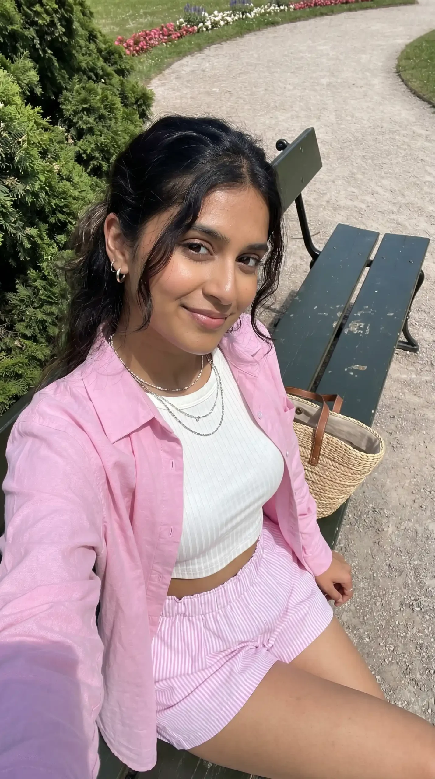 Woman wearing light pink oversized shirt with white crop top and pink striped shorts in park