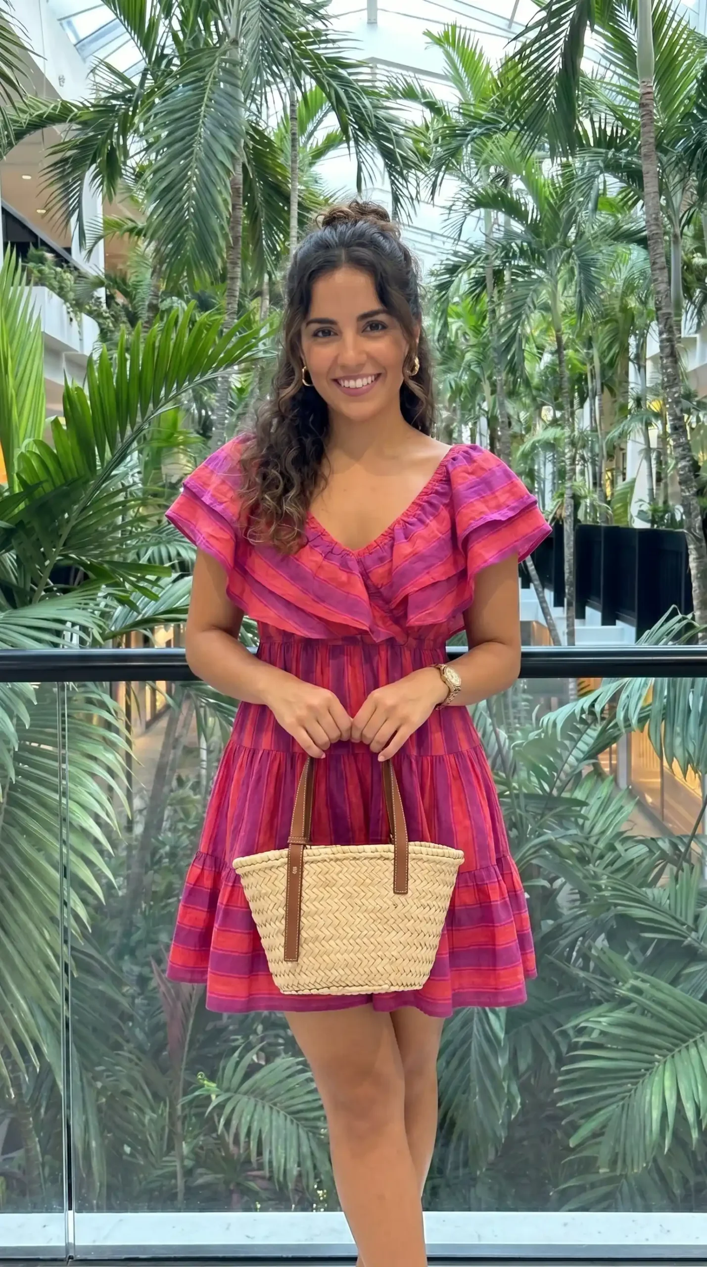 Woman wearing pink and red striped tiered ruffle dress in tropical setting