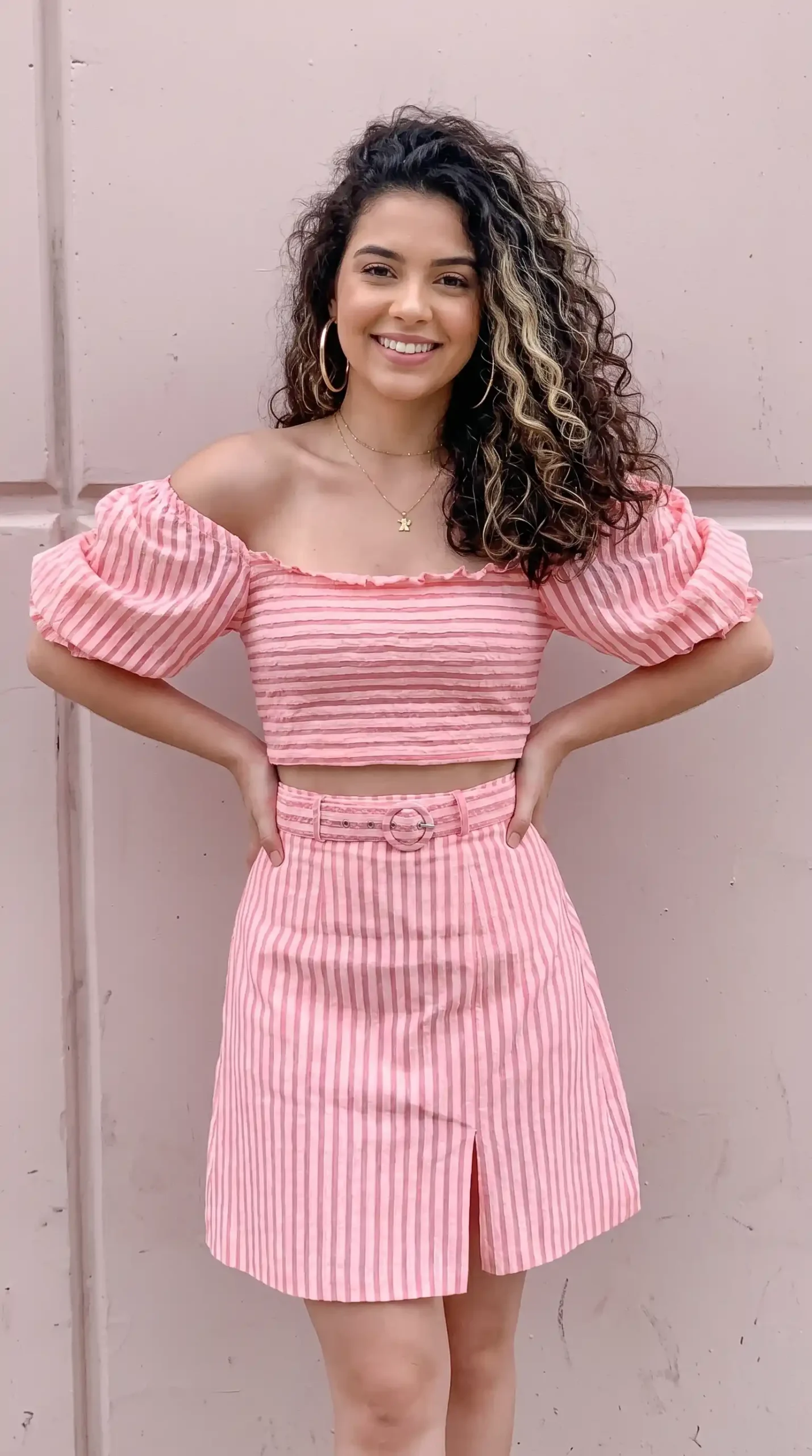 Woman wearing pink and white striped off shoulder puff sleeve crop top and matching mini skirt co-ord set