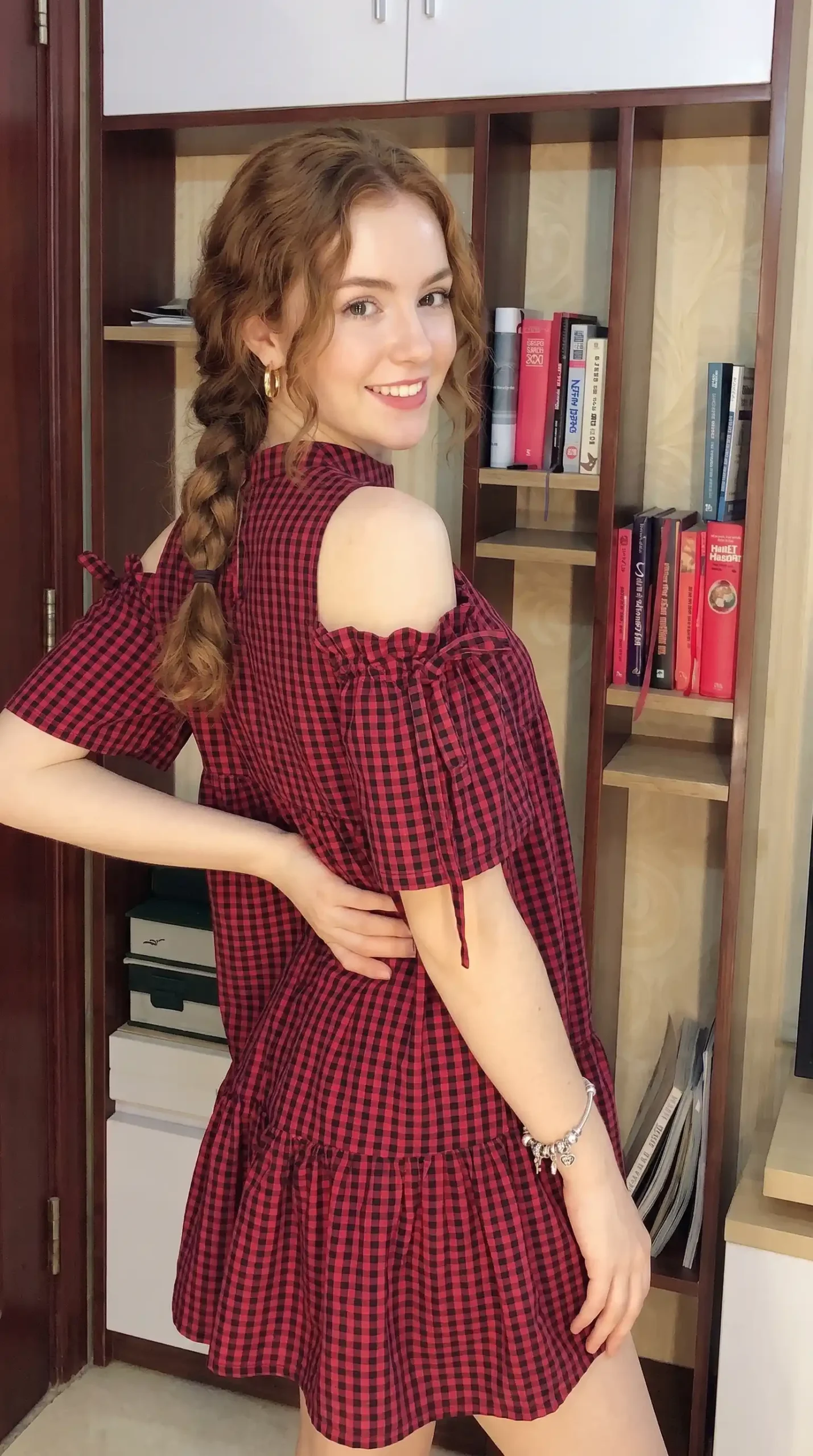 Woman wearing red gingham check mini dress with puff sleeves and tiered skirt