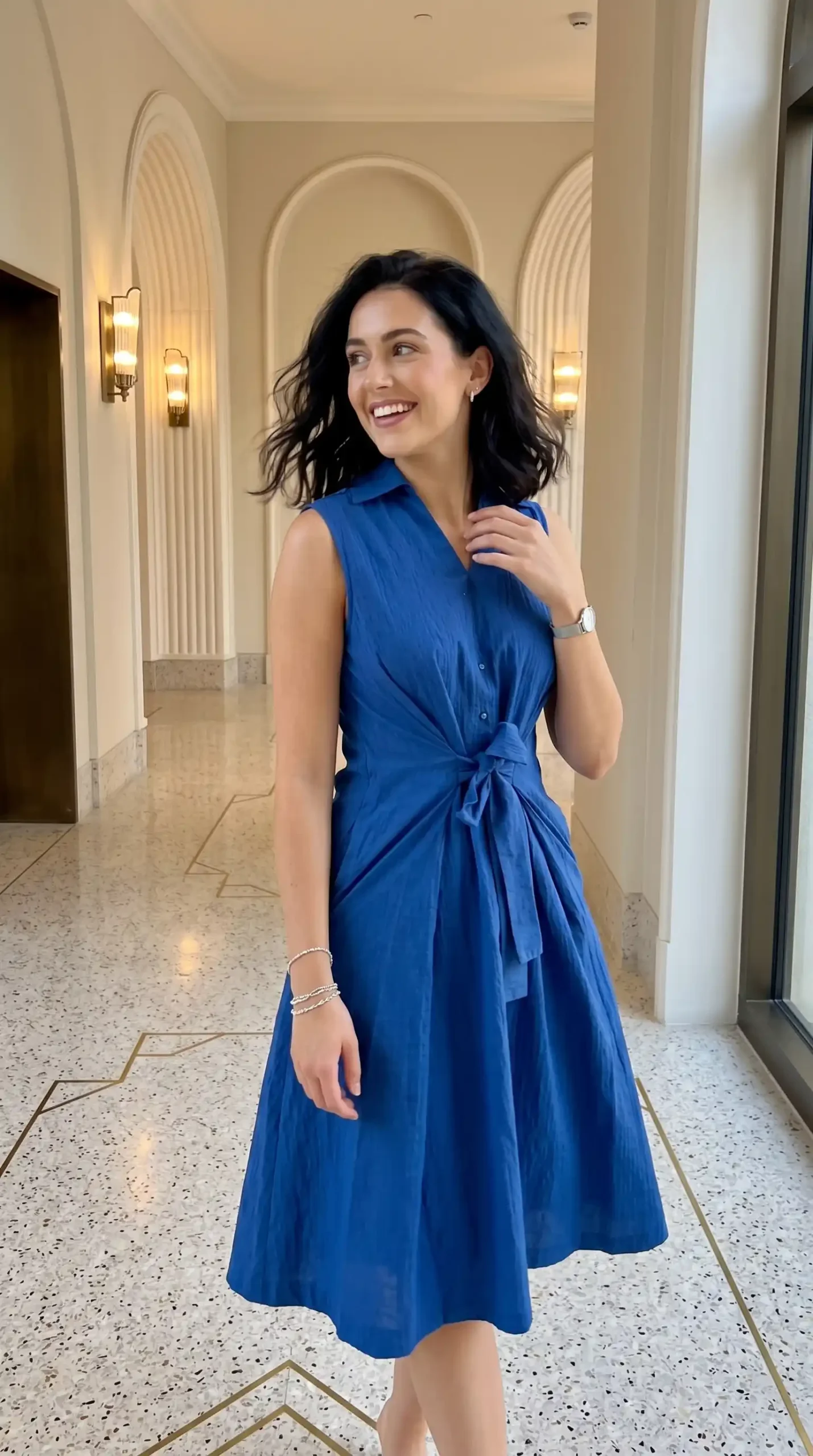 Woman wearing royal blue sleeveless collared tie waist A line midi dress indoors in summer