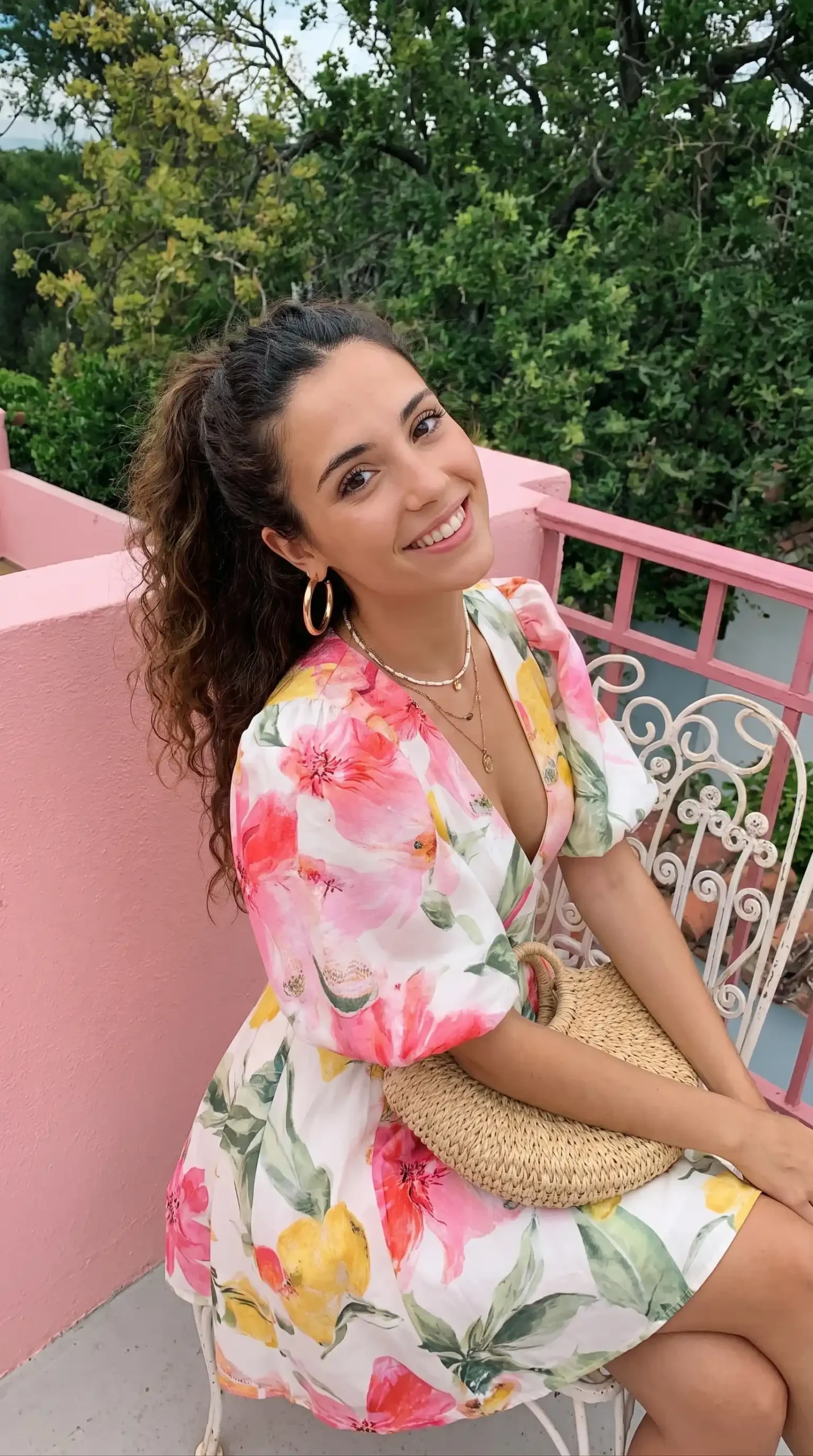 Woman wearing white floral print dress with puff sleeves on pink porch