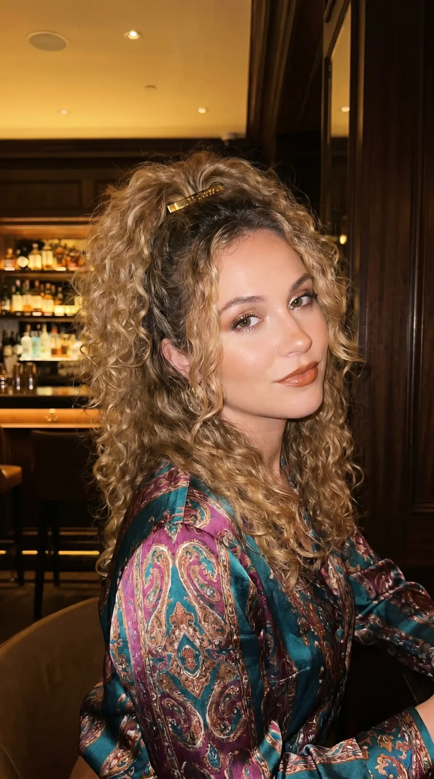Woman with caramel blonde voluminous curly half up hairstyle