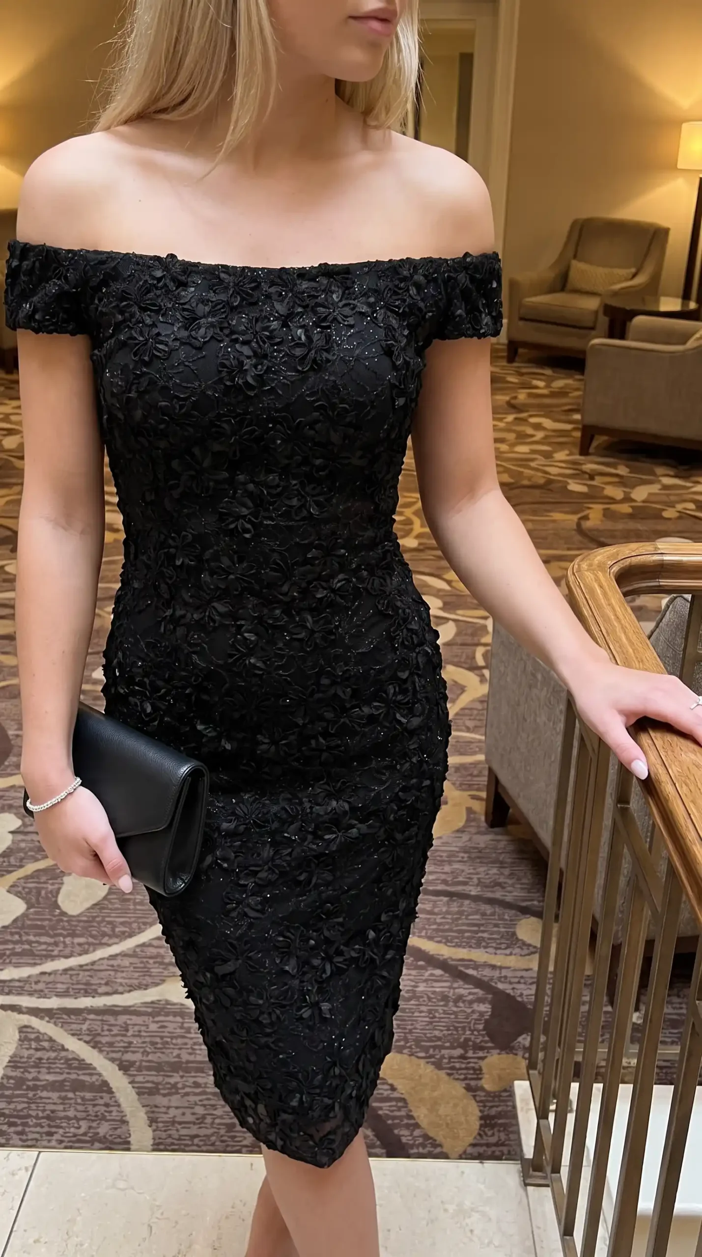 Woman wearing black 3D floral applique off shoulder bodycon midi dress with black clutch